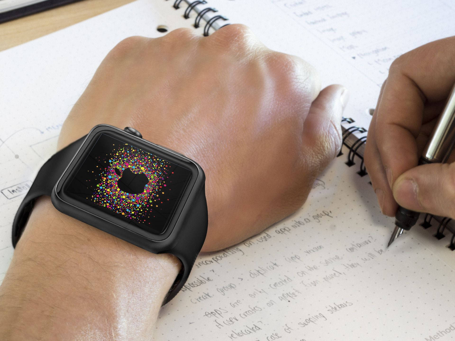 Apple Watch 動態 桌布 壁紙 — 一隻手在螺旋筆記本上寫筆記，同時佩戴黑色Apple Watch，螢幕上顯示色彩繽紛的粒子動畫。