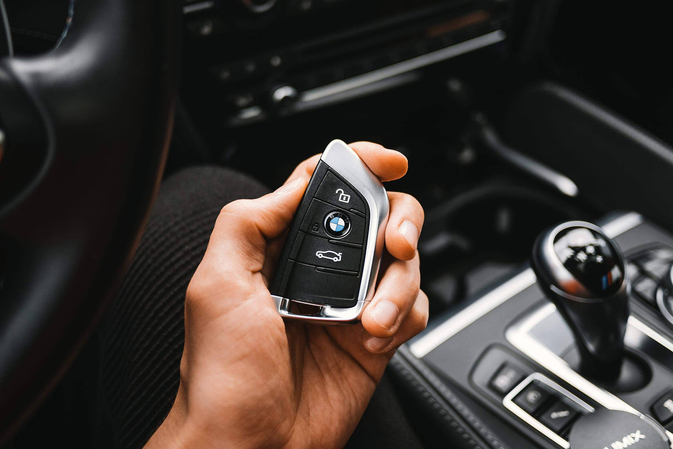 Bmw Cars 桌布 壁紙 — 一隻手在豪華車的時尚黑色內飾（皮革和金屬裝飾）中握著BMW車鑰匙。