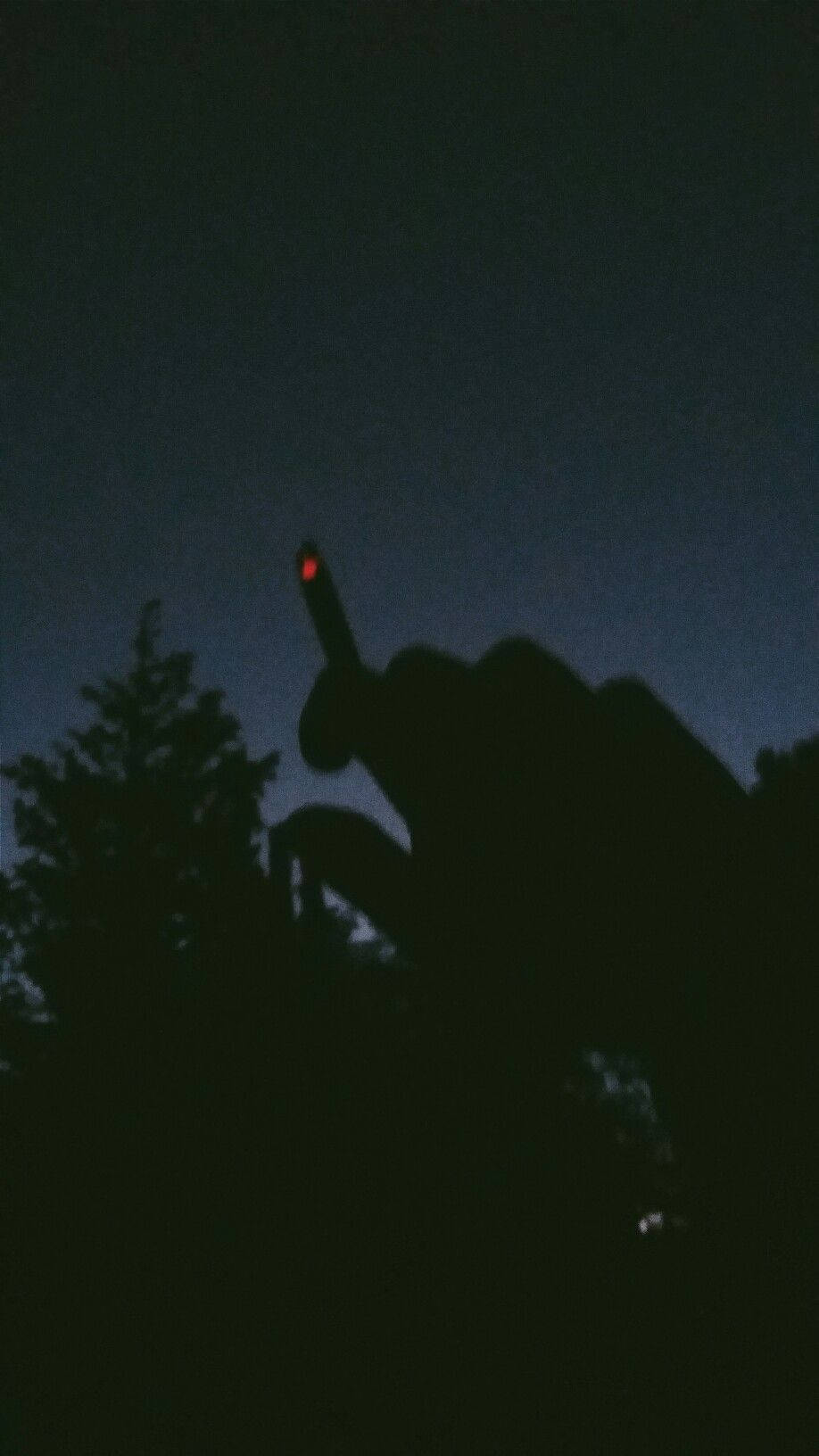 暗黑風格 桌布 壁紙 — 一隻手在黑暗暮色天空的襯托下形成剪影，握著一根發光的紅色香煙。