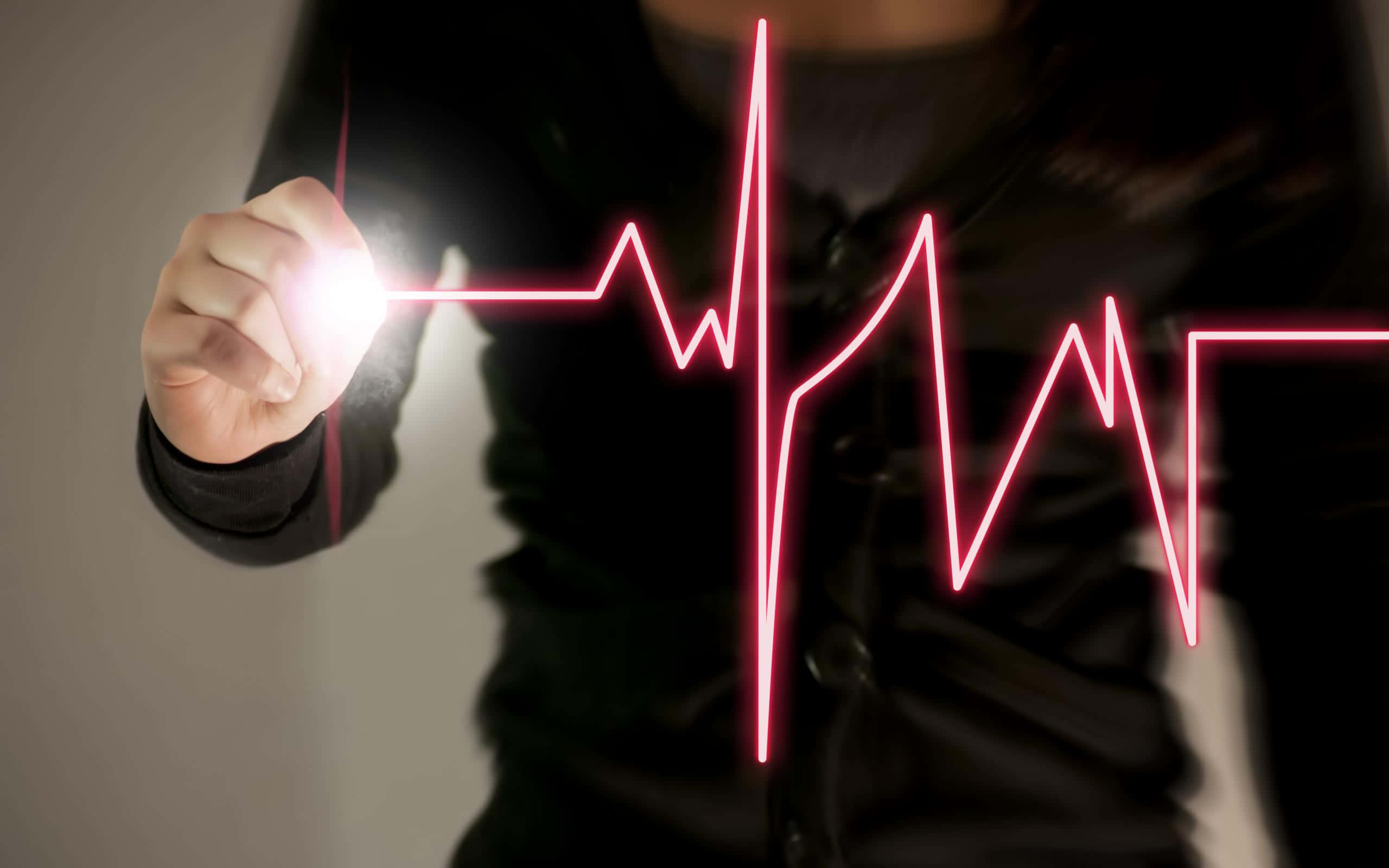 Heart Rate 桌布 壁紙 — 一隻手在黑暗的螢幕上畫出一條發光的紅色心跳線，指尖散發出明亮的光芒。