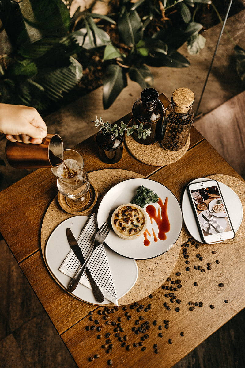 Dish 桌布 壁紙 — 一隻手將咖啡倒入玻璃杯，旁邊放著一碟糕點和散落的咖啡豆，在質樸的木桌上。