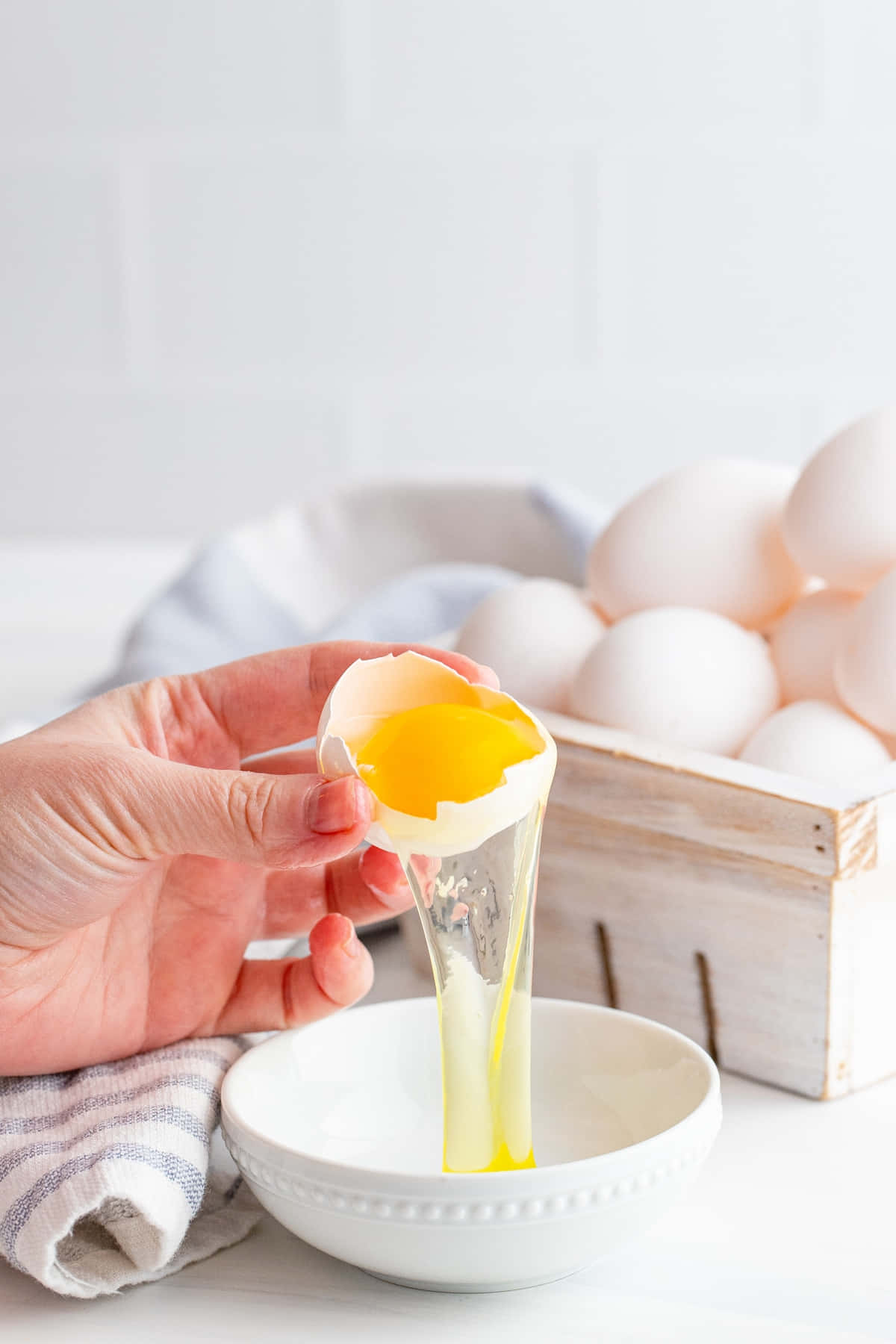Egg White 桌布 壁紙 — 一隻手小心地將鮮黃色的蛋黃倒入一個白色碗中，透明的蛋白在明亮的白色瓷磚背景下滴落。