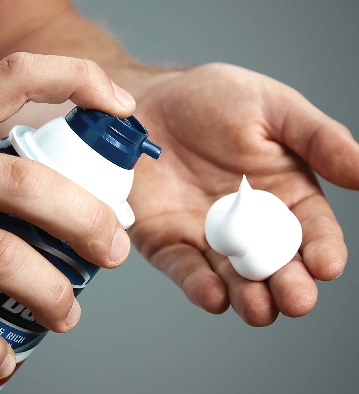 Shaving Cream 桌布 壁紙 — 一隻手從藍白罐中擠出完美白色泡沫到另一隻手掌上，背景為中性灰色。