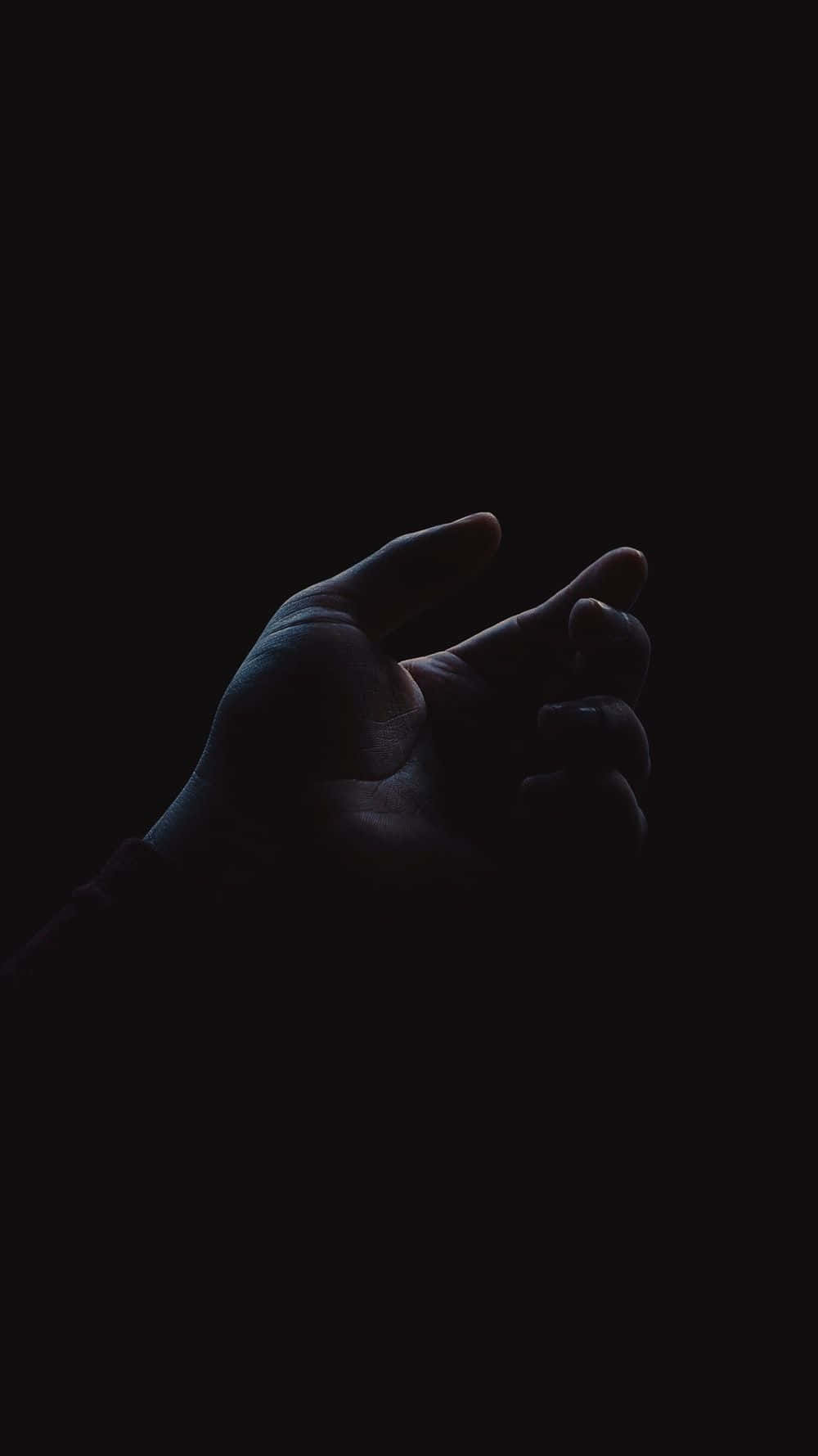 Vantablack 桌布 壁紙 — 一隻手從黑暗中伸出，手指微微彎曲，彷彿在觸摸看不見的東西。