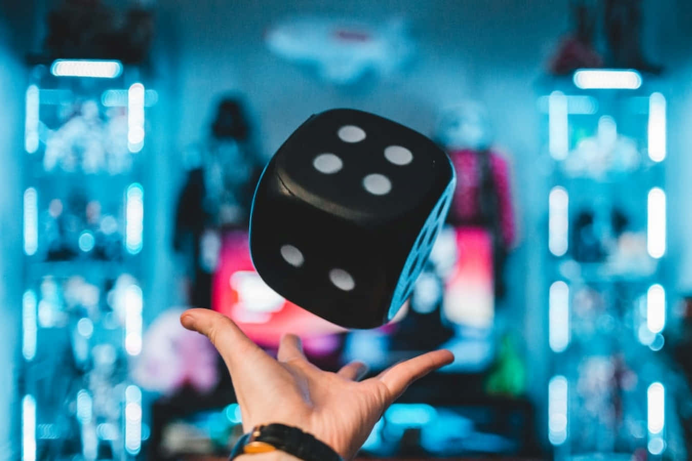 game 桌布 壁紙 — 一隻手懸浮在一個黑色骰子下方，骰子顯示四點，懸浮在半空中，背景是發光的藍色霓虹燈。