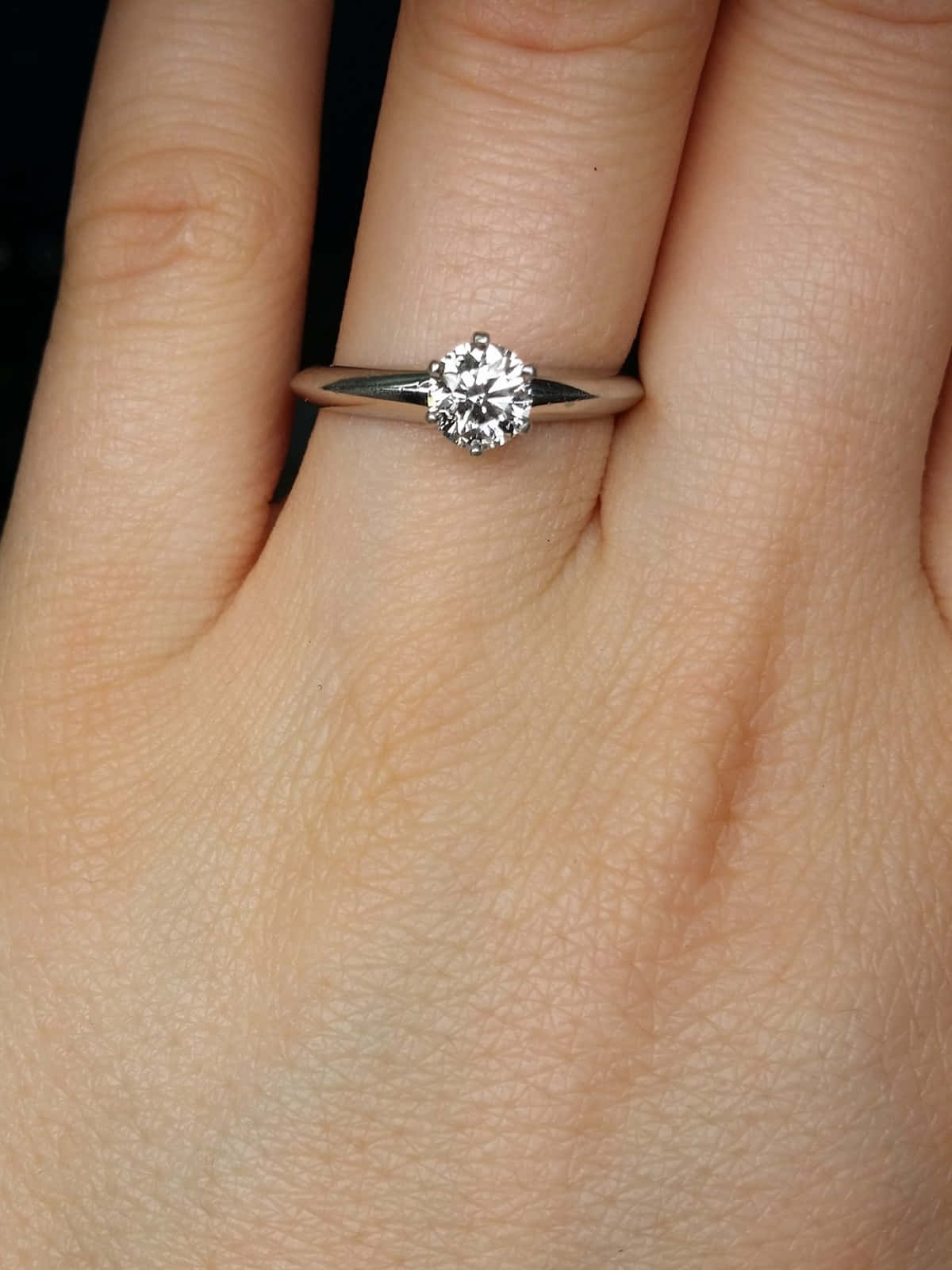 rings 桌布 壁紙 — 一隻手戴著單鑽訂婚戒指的特寫，戒指配有時尚的銀色指環。