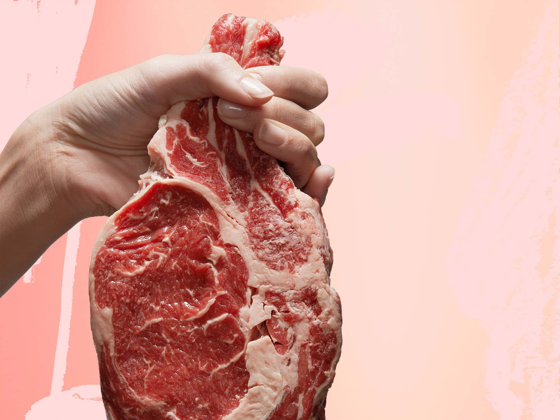 Red Meat 桌布 壁紙 — 一隻手抓住一塊帶有大理石花紋脂肪的生牛肉排，背景是柔軟的粉紅色紋理。