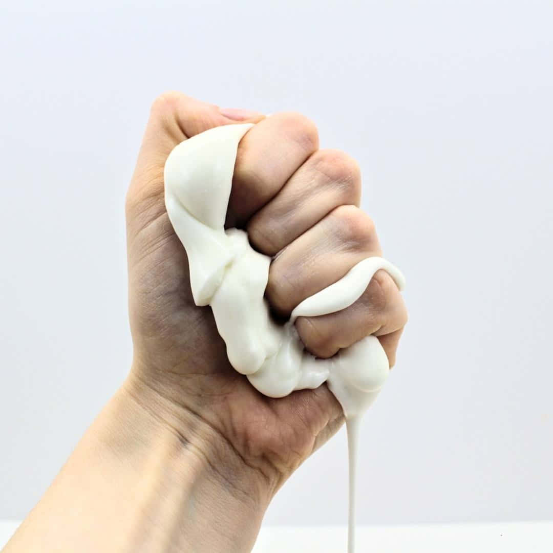 hand 桌布 壁紙 — 一隻手抓住並擠壓厚厚的白色黏液，背景為純白色，有一滴落下。