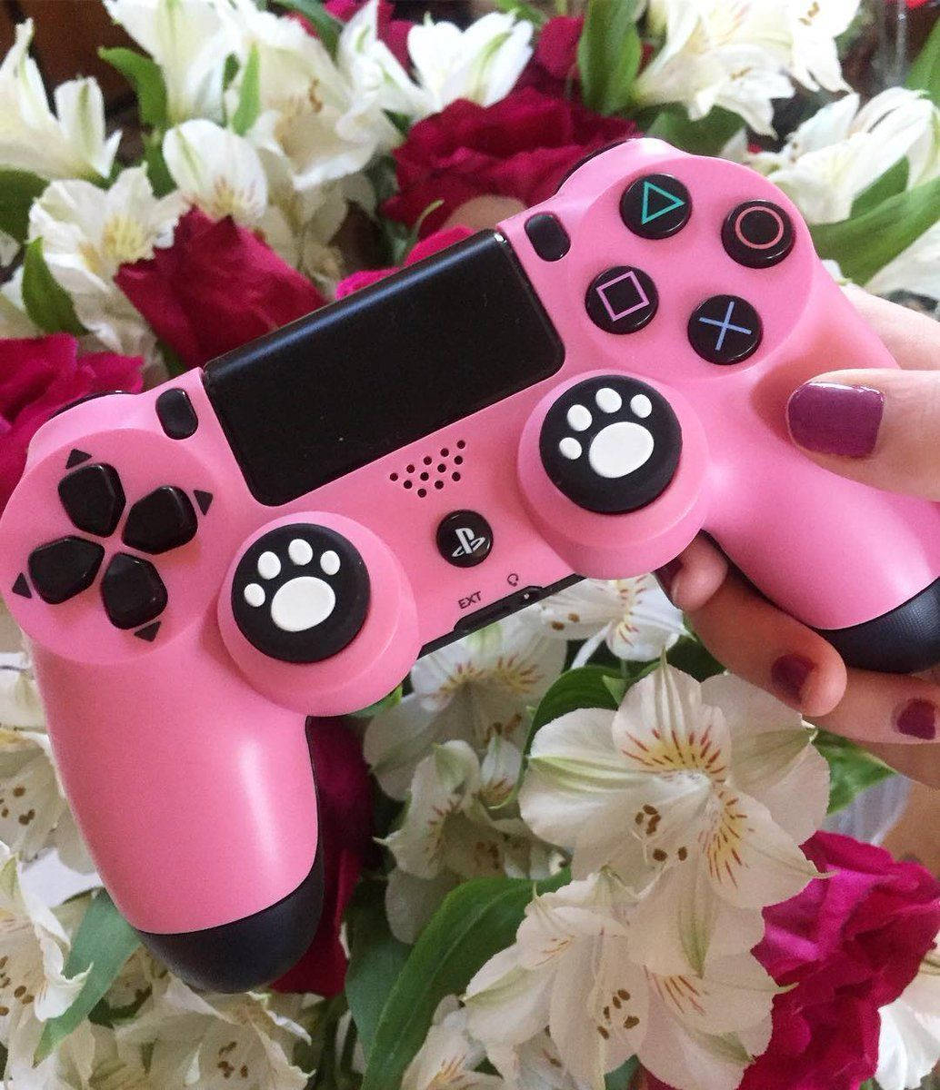 Aesthetic Girly 桌布 壁紙 — 一隻手拿著一個帶有爪印握把的粉紅色PlayStation控制器，背景是紅色和白色的花朵。