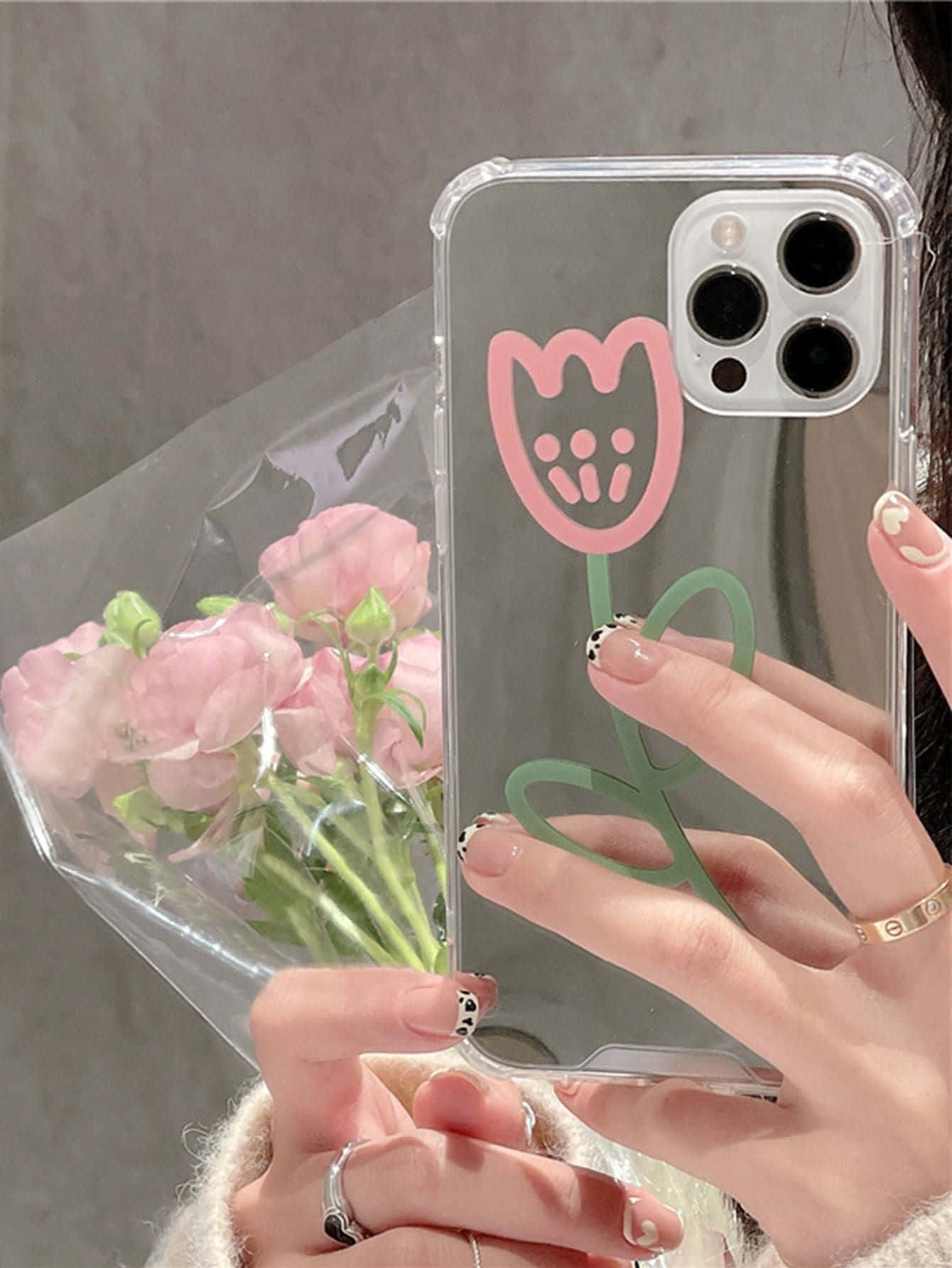 Phone Case 桌布 壁紙 — 一隻手拿著一個帶有粉紅色鬱金香圖案的透明手機殼，同時握著一束粉紅色的花。