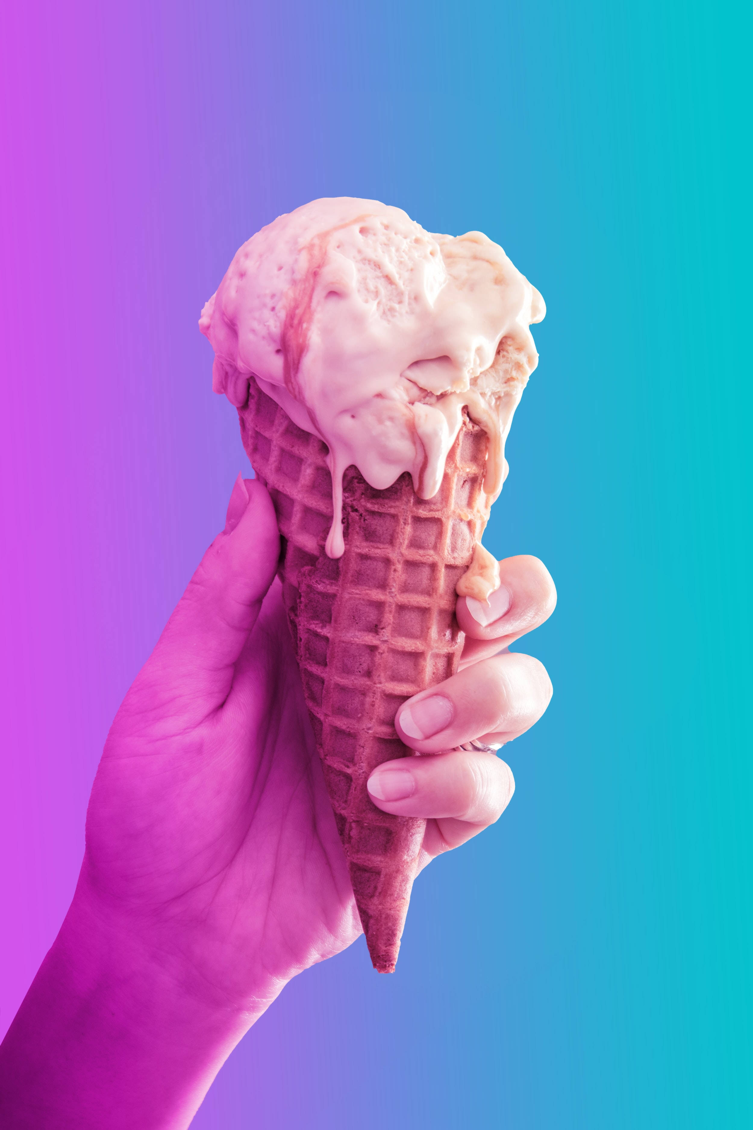 Ice Cream 桌布 壁紙 — 一隻手拿著一個正在融化的草莓冰淇淋甜筒，背景是充滿活力的紫色到青色漸變。