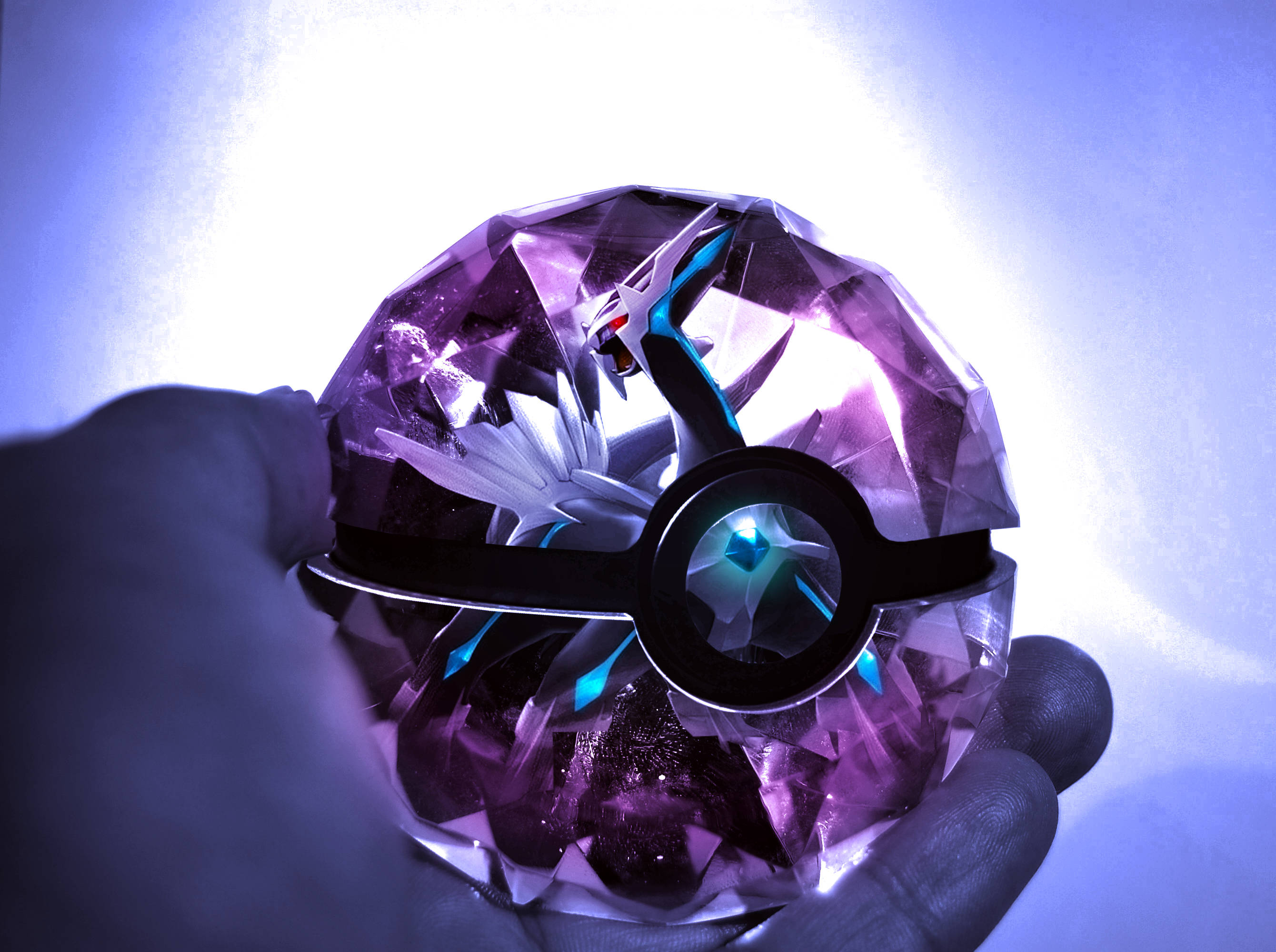 Dialga 桌布 壁紙 — 一隻手拿著一個發光的紫色鑽石形狀的精靈球，裡面顯露出一條雄偉的白色和藍色龍。