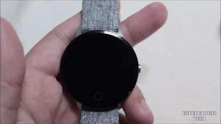 手拿著帶灰色織物錶帶的黑色智慧手錶。 — 智慧手錶 GIF 壁紙