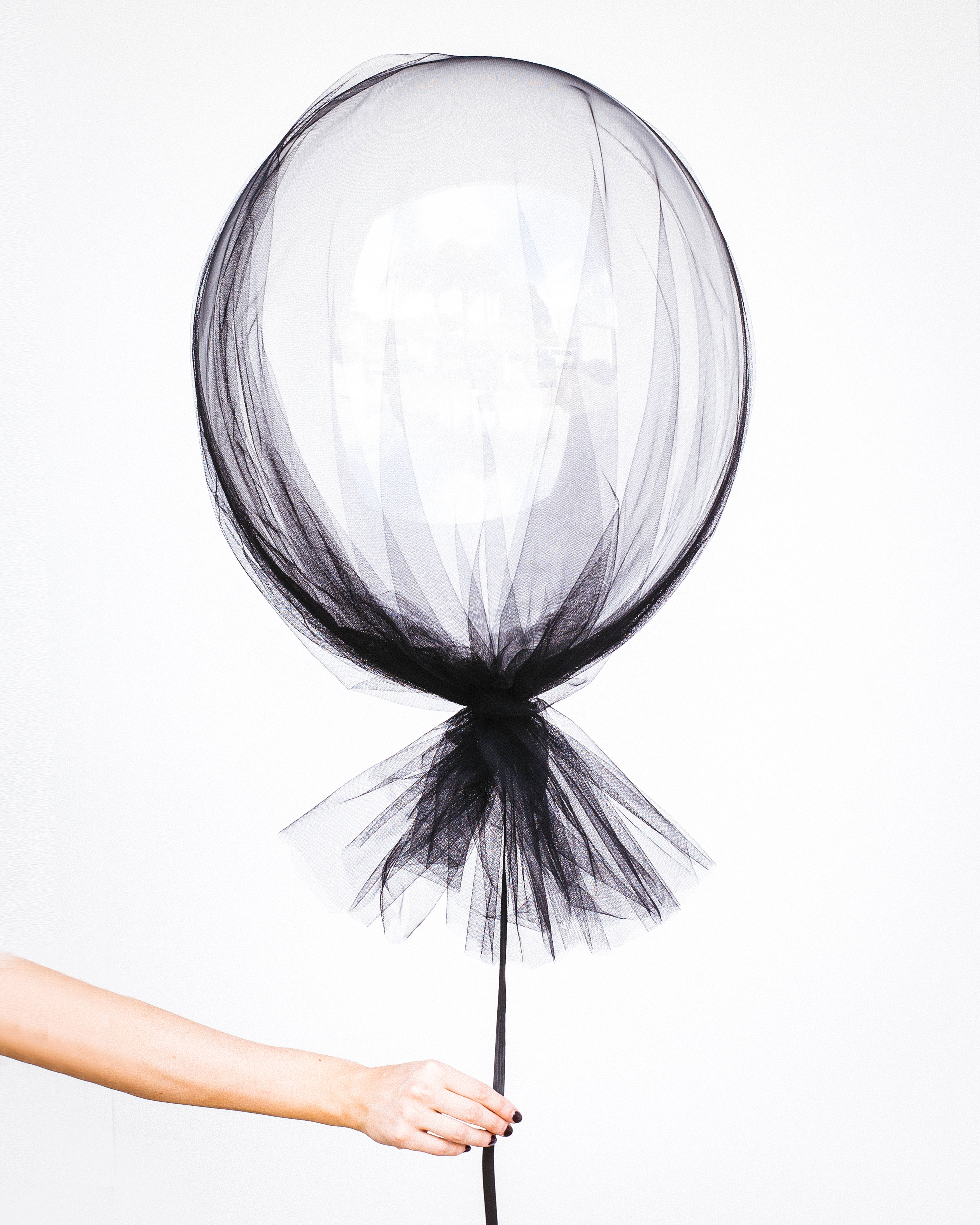 Balloon 桌布 壁紙 — 一隻手拿著一個黑色薄紗氣球，襯托在純白色背景上，營造出簡約而優雅的對比。
