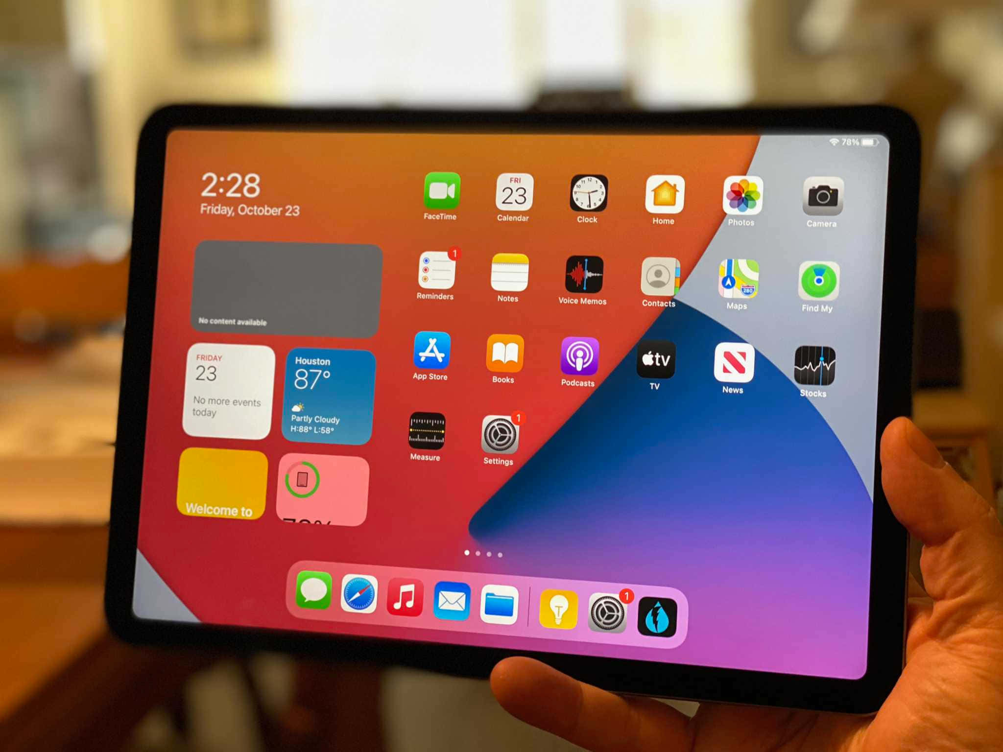 iPad 桌布 壁紙 — 一隻手拿著一台iPad，顯示色彩繽紛的主螢幕，帶有應用程式圖示、天氣小工具和時間，背景為漸層色。