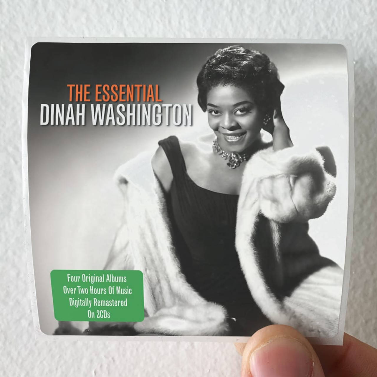 Legend 桌布 壁紙 — 一隻手拿著一張Dinah Washington的復古專輯封面，她穿著黑色連衣裙和白色毛皮披肩，在攝影棚背景下溫暖地微笑。