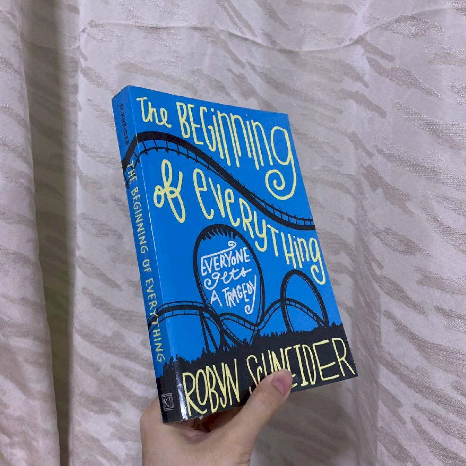 書本 桌布 壁紙 — 一隻手拿著一本亮藍色的書，書名為《The Beginning of Everything》，背景是帶有紋理的白色布料。