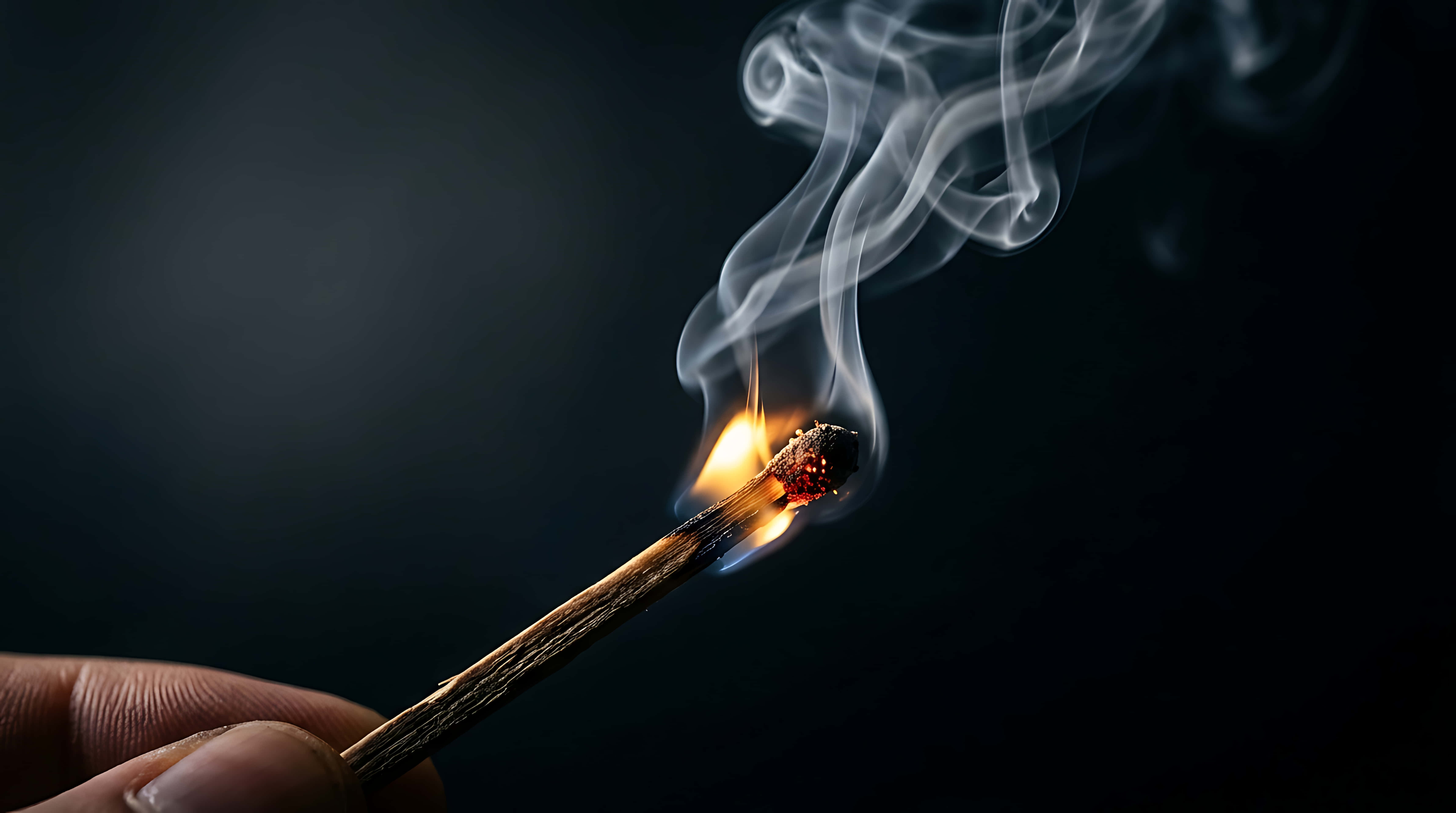 Flame 桌布 壁紙 — 一隻手拿著一根點燃的火柴，在黑暗背景下投射出溫暖的光和捲曲的煙霧。