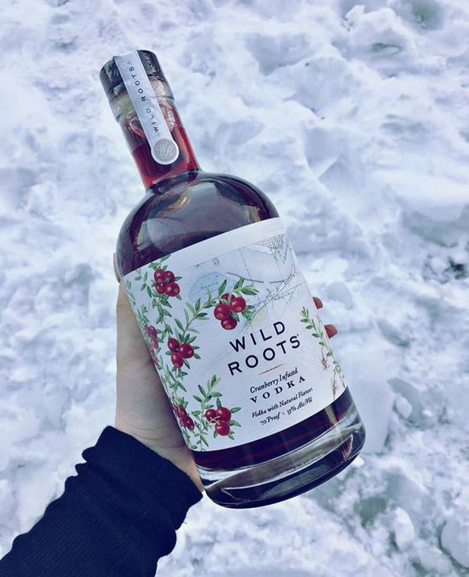 bottle 桌布 壁紙 — 一隻手拿著一瓶蔓越莓注入伏特加，背景是雪景和清晰的冬日光線。