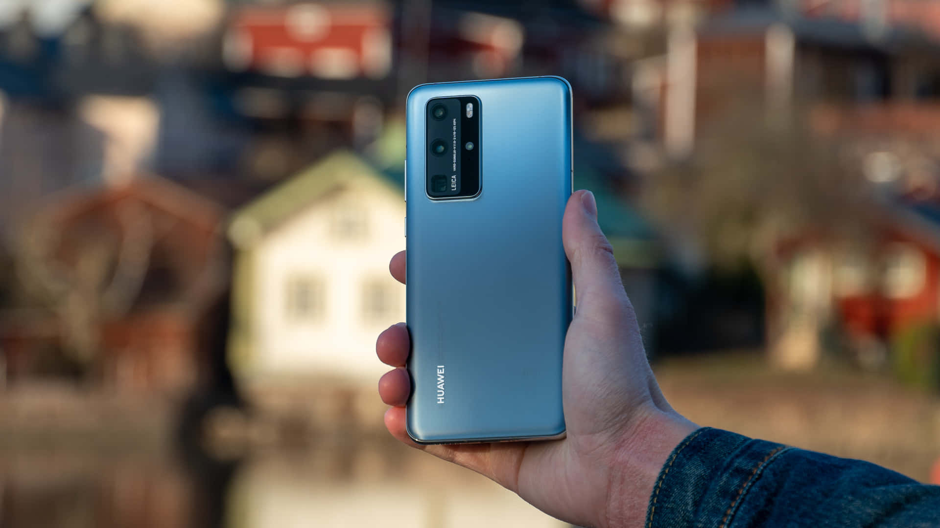 手拿著藍色Huawei智慧型手機，相機模組可見。