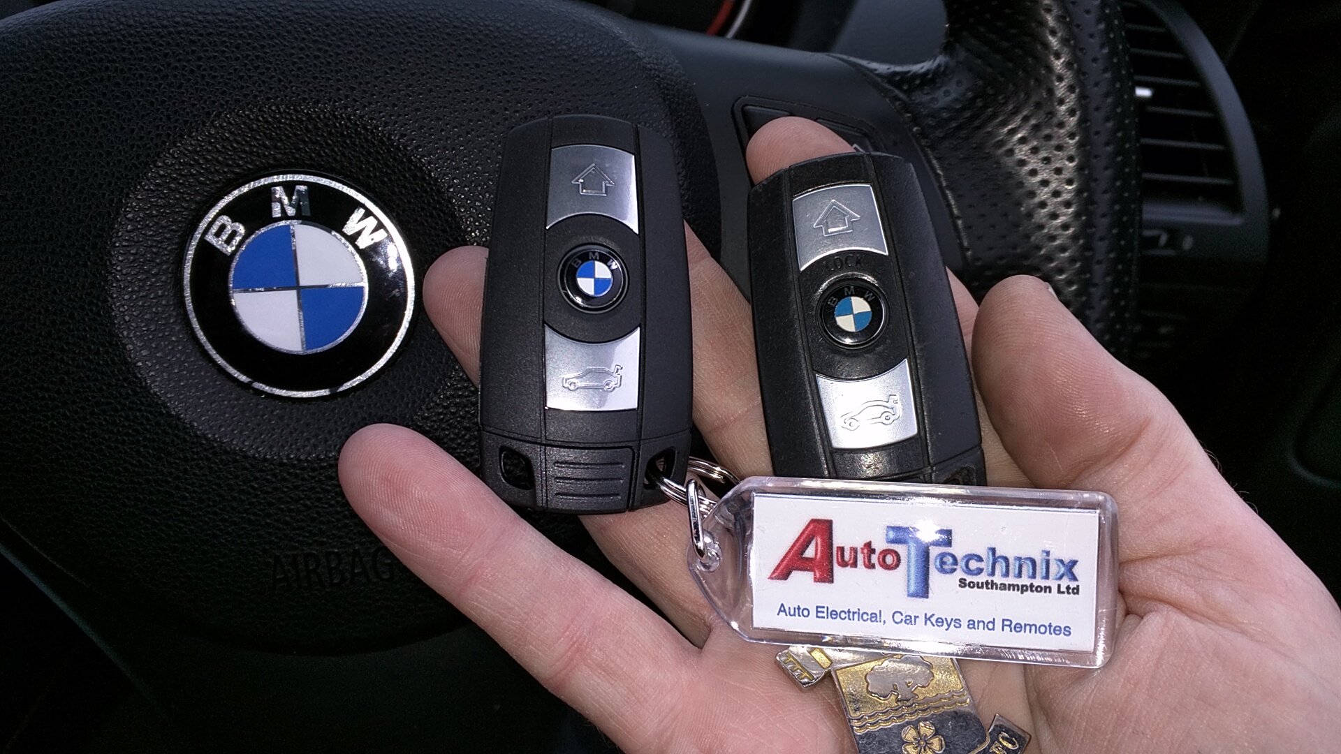 手在方向盤附近拿著帶有Auto Technix鑰匙圈的BMW車鑰匙。 — BMW 動圖 壁紙