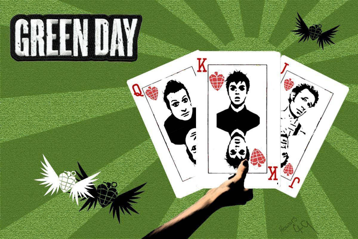 Green Day 桌布 壁紙 — 一隻手拿著印有Green Day樂團成員的撲克牌，背景是綠色放射狀圖案，帶有飛翔的手榴彈圖標。