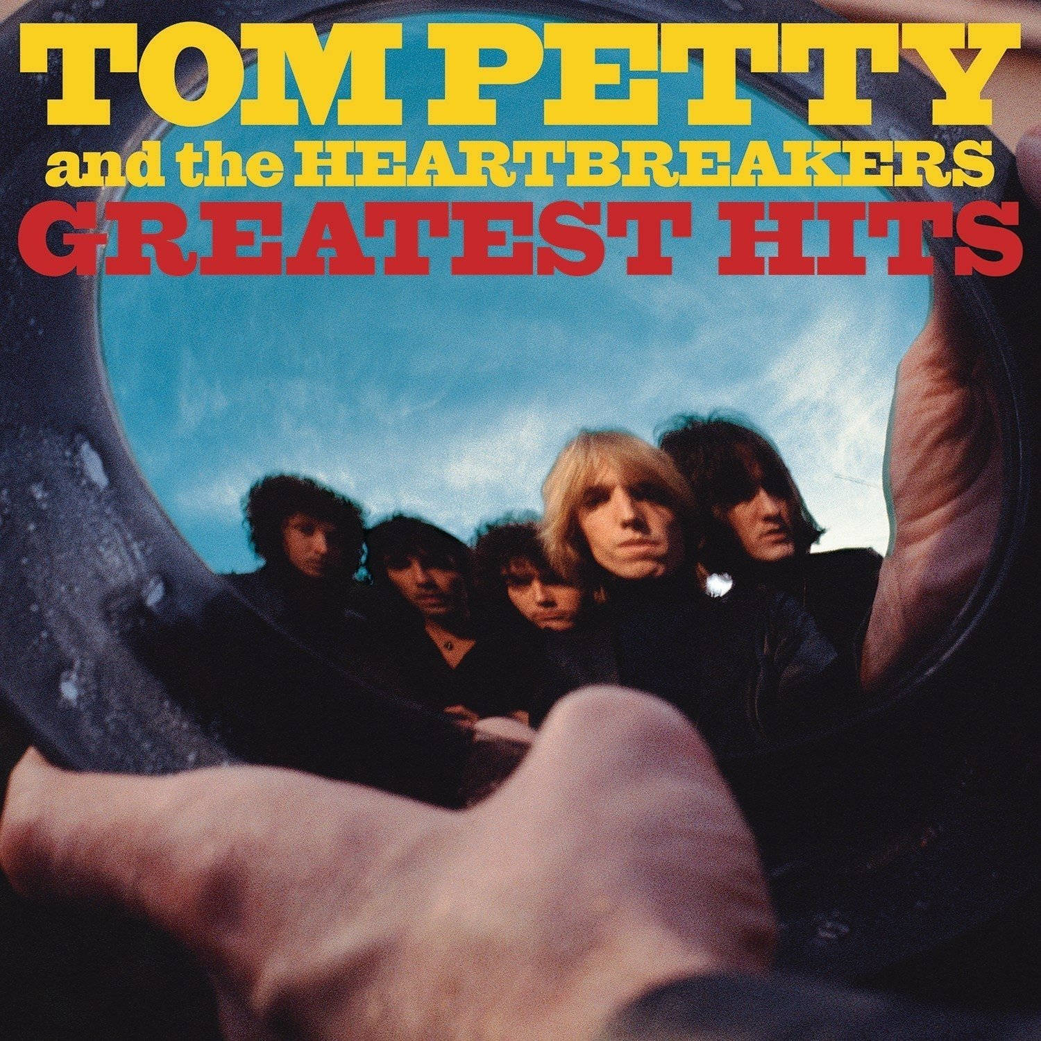 rock n roll 桌布 壁紙 — 一隻手拿著圓形鏡子，反射出Tom Petty and the Heartbreakers，背景是藍天，並有粗體黃色和紅色的專輯文字。