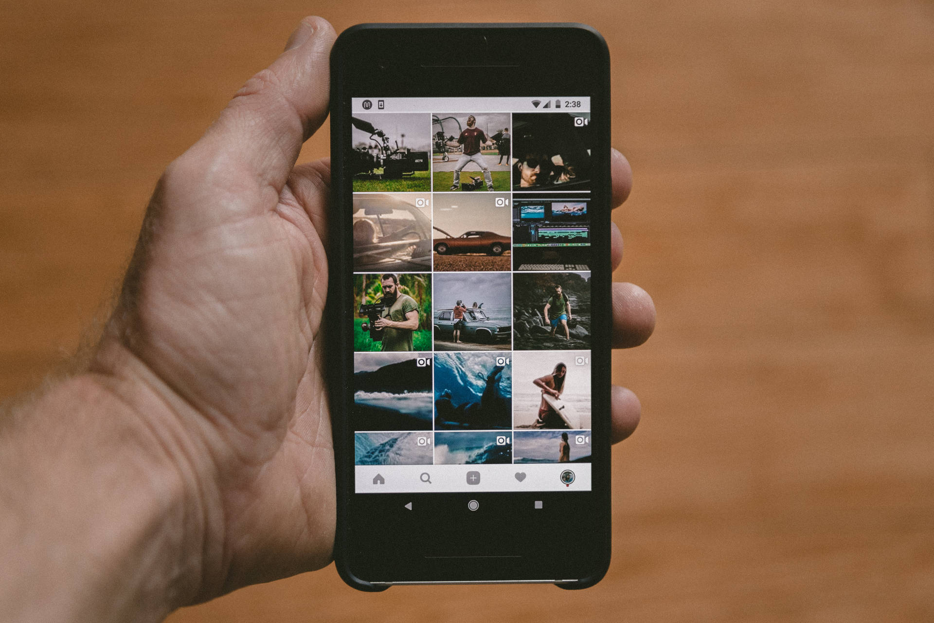 手拿著智慧型手機在木質表面上顯示照片庫。 — Google pixel 壁紙