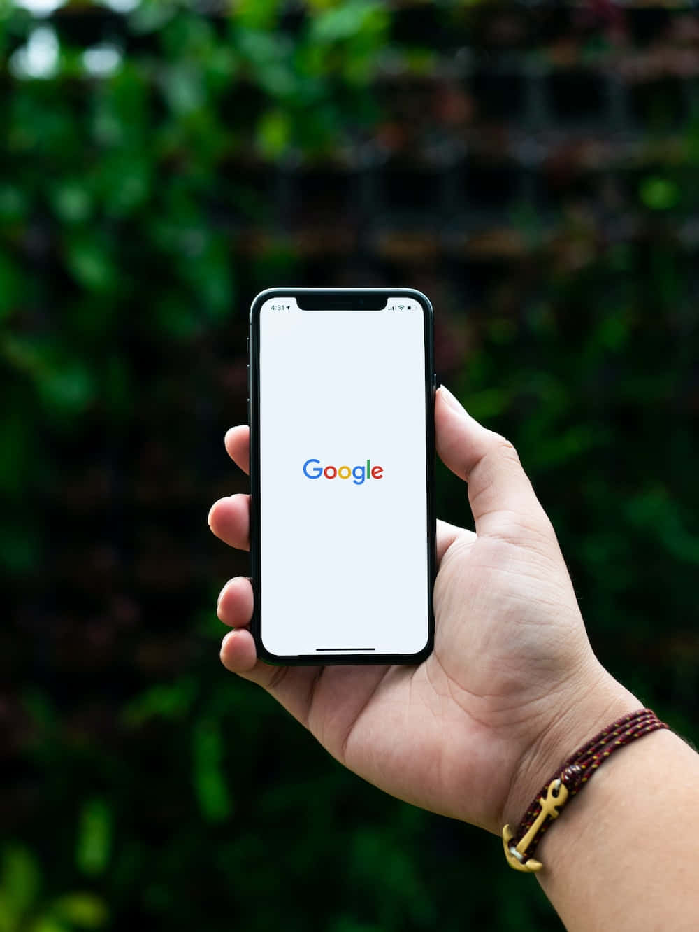 手拿著帶有Google標誌的手機，在綠色戶外環境中 — Google Meet 壁紙