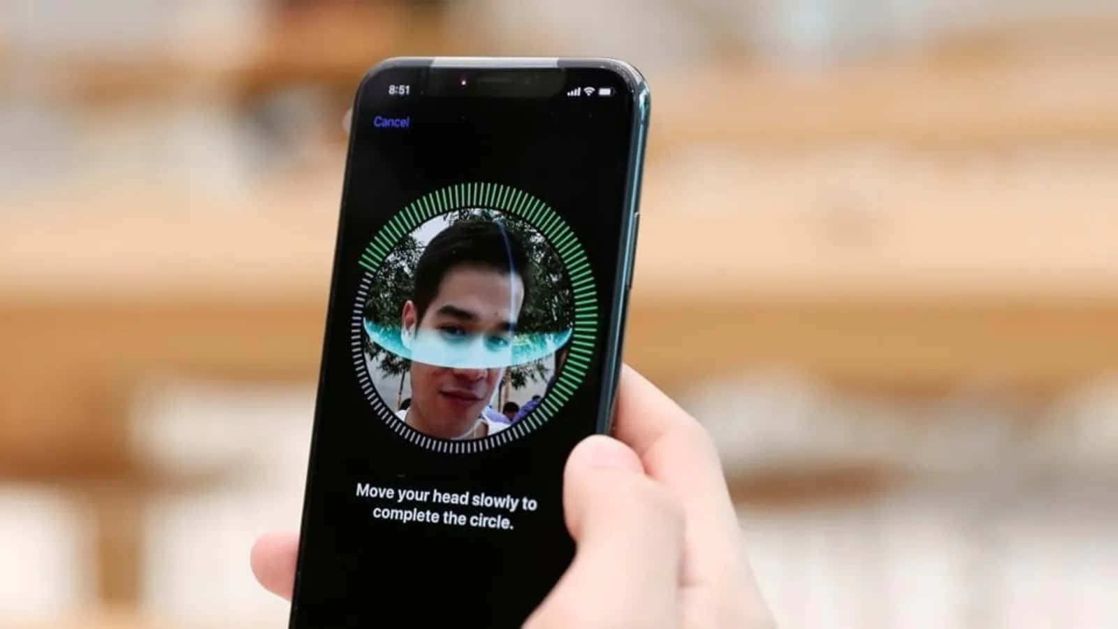 Face Id 桌布 壁紙 — 一隻手拿著智慧型手機，顯示臉部辨識設定畫面，一個人的臉在綠色掃描圓圈內。