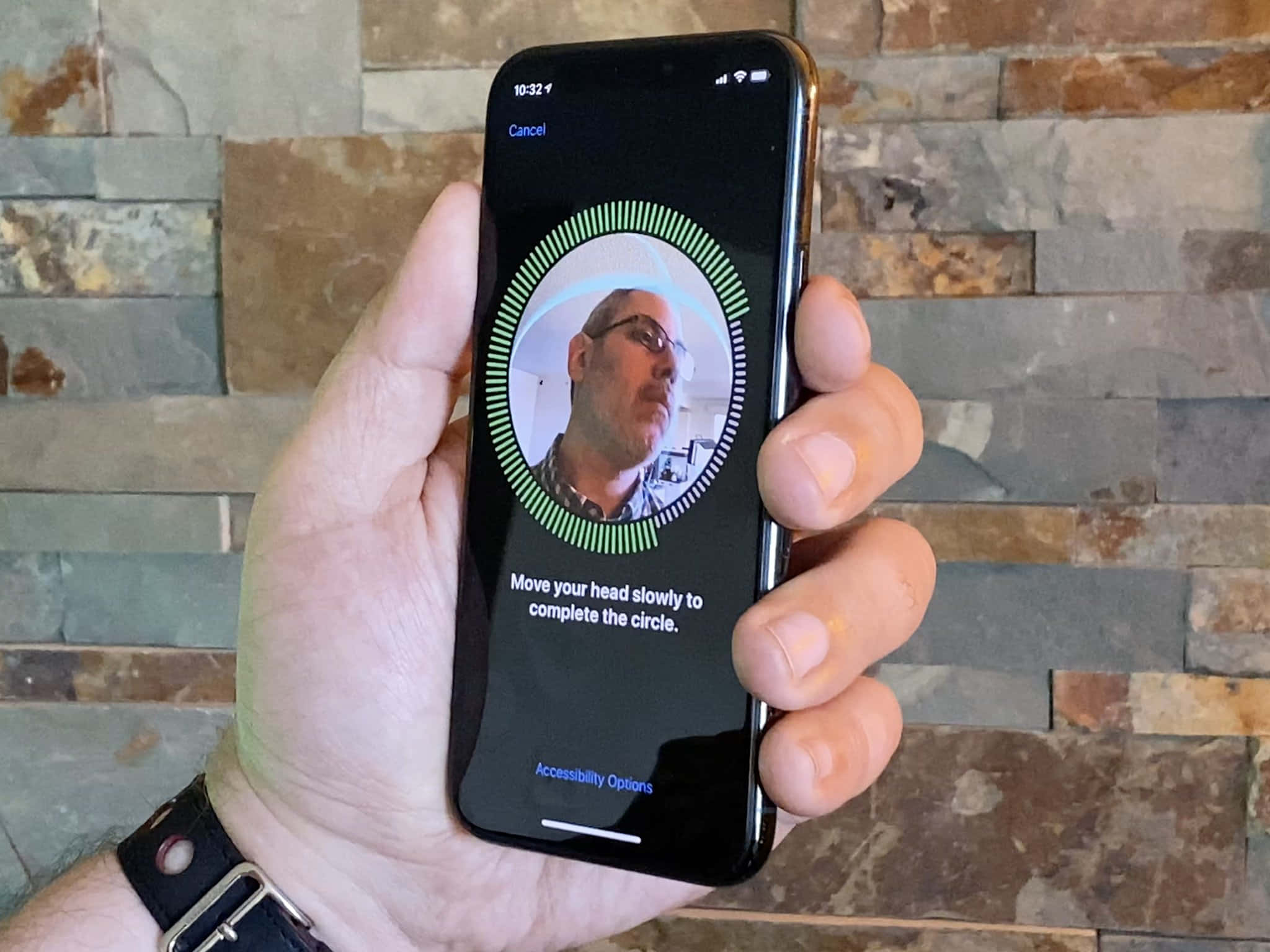 Face Id 桌布 壁紙 — 一隻手拿著智慧型手機，顯示臉部辨識設定畫面，背景為石牆。