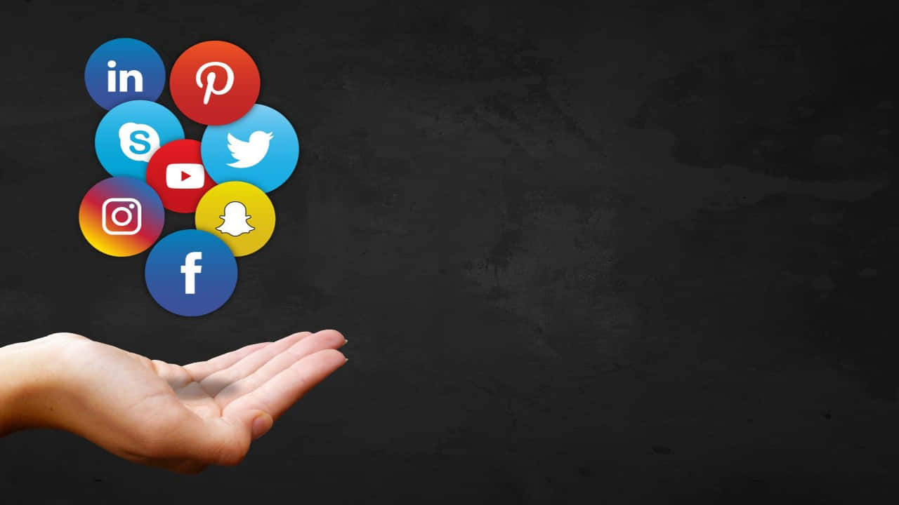 Social Media Logos 桌布 壁紙 — 一隻手拿著浮動的社交媒體圖示，背景為深色紋理。