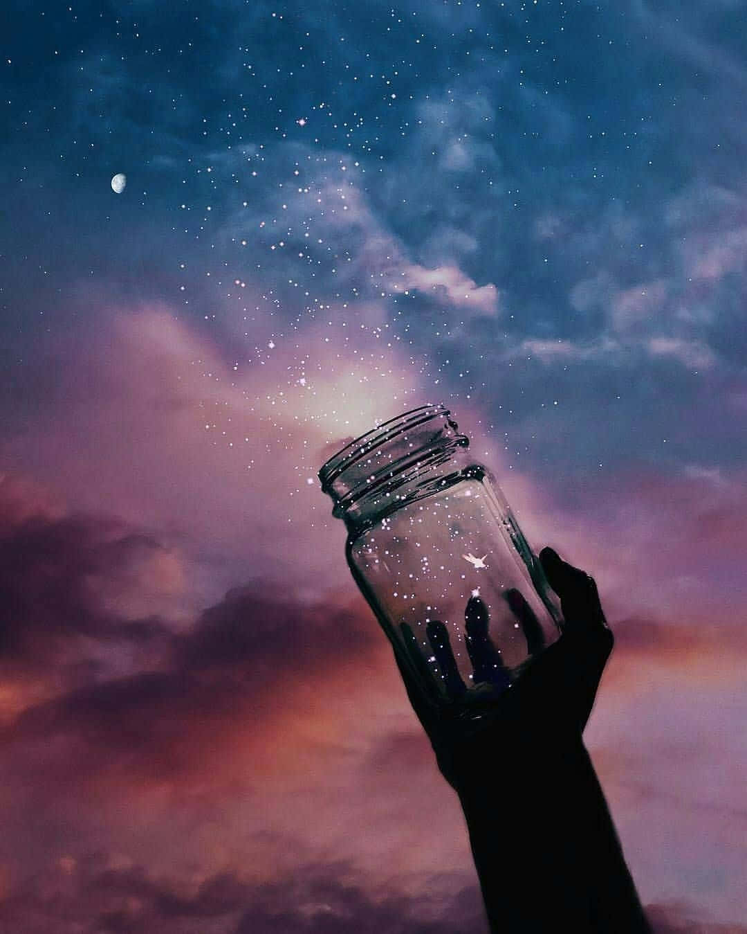 美麗 桌布 壁紙 — 一隻手拿著玻璃罐，捕捉在暮色天空中的流星，天空有柔軟的雲朵和一彎新月。