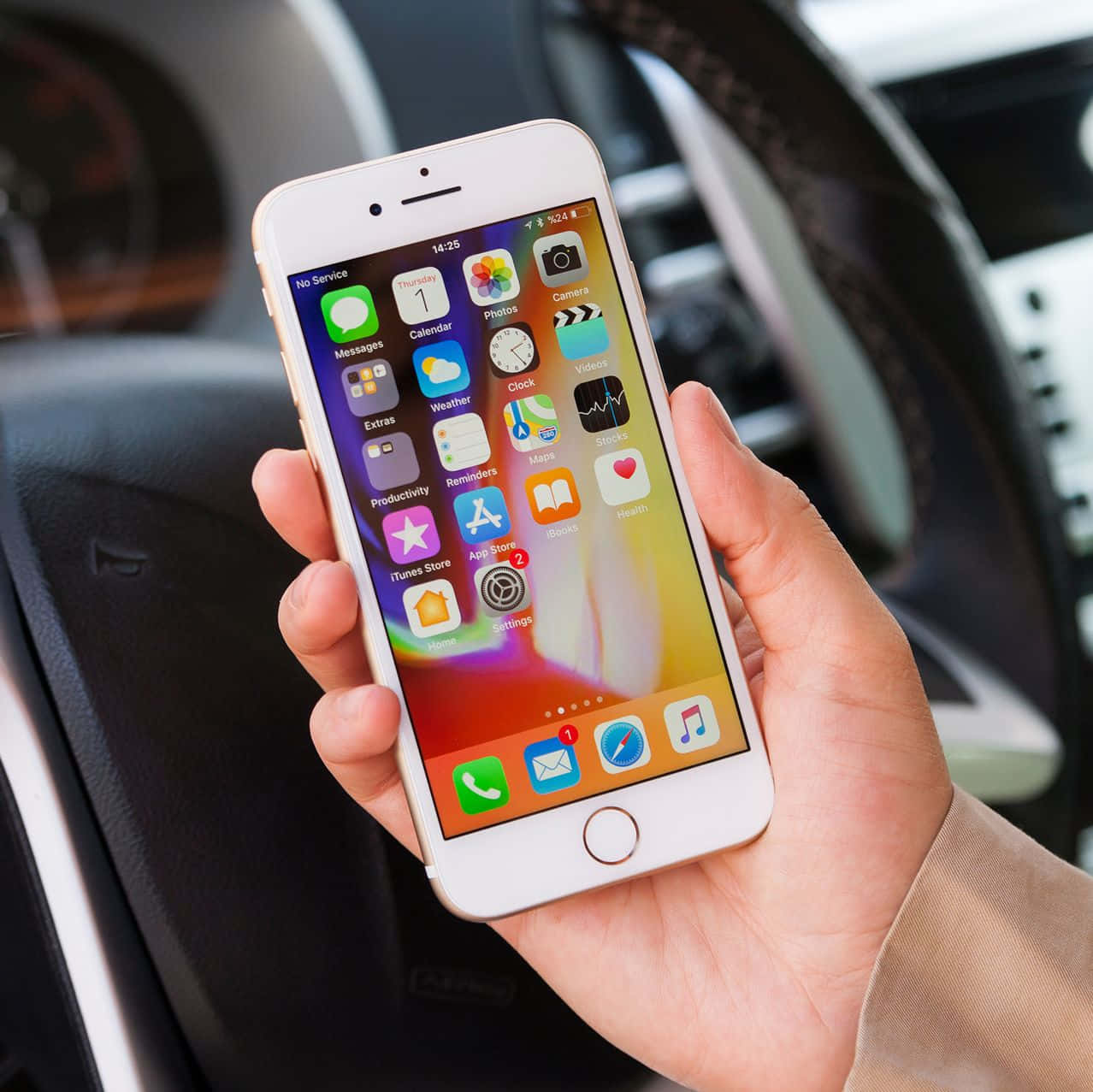 手機 桌布 壁紙 — 一隻手拿著白色iPhone，在車內顯示色彩繽紛的應用程式圖標，背景是模糊的方向盤。