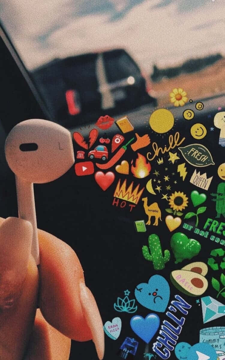 音樂美學 桌布 壁紙 — 一隻手拿著白色耳機貼在手機上，手機上貼滿了色彩繽紛的貼紙，有愛心、太陽和 chill 氛圍。