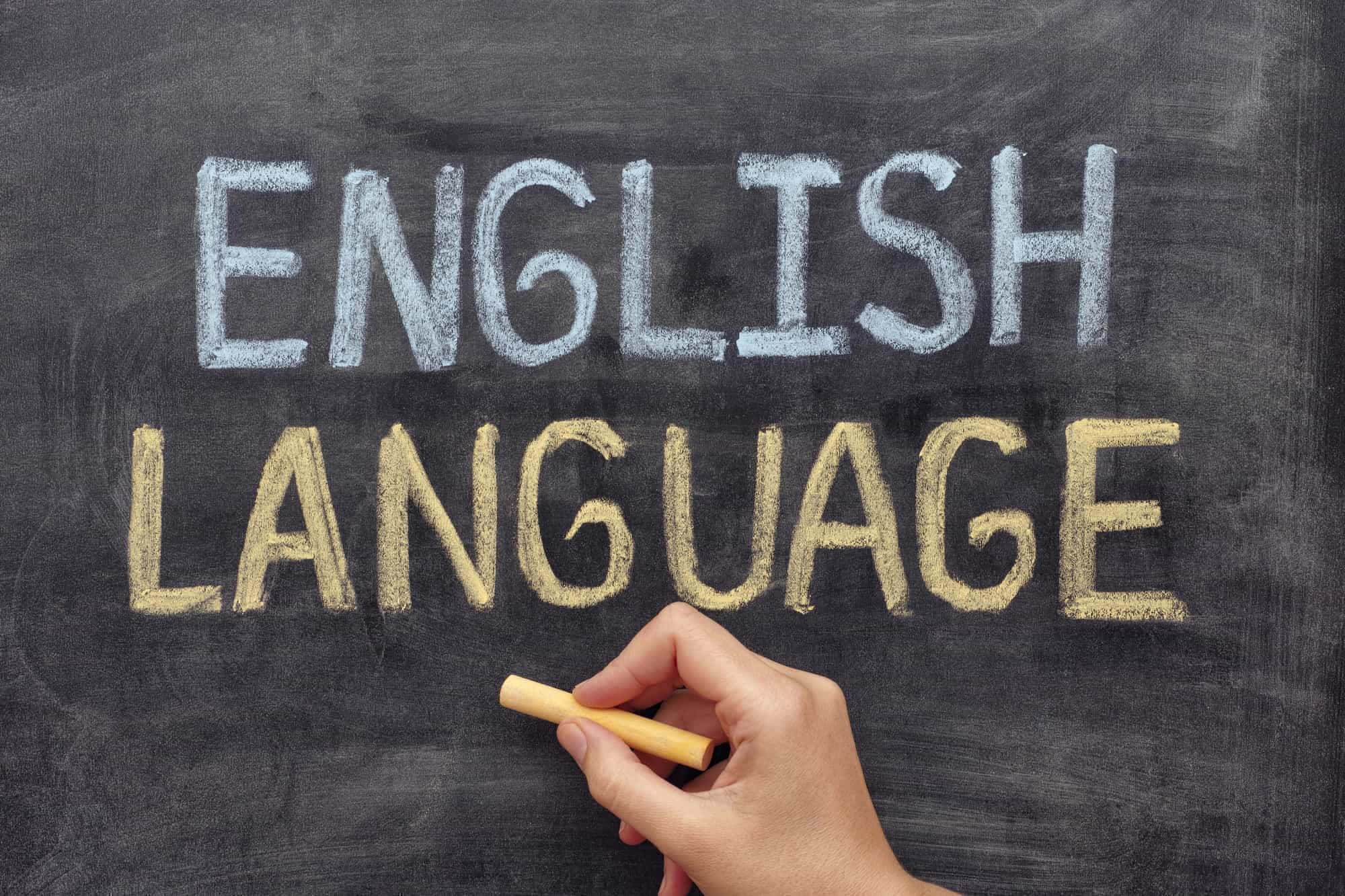 Learning 桌布 壁紙 — 一隻手拿著粉筆，在帶有紋理的黑板上用粗體字寫著「ENGLISH LANGUAGE」。