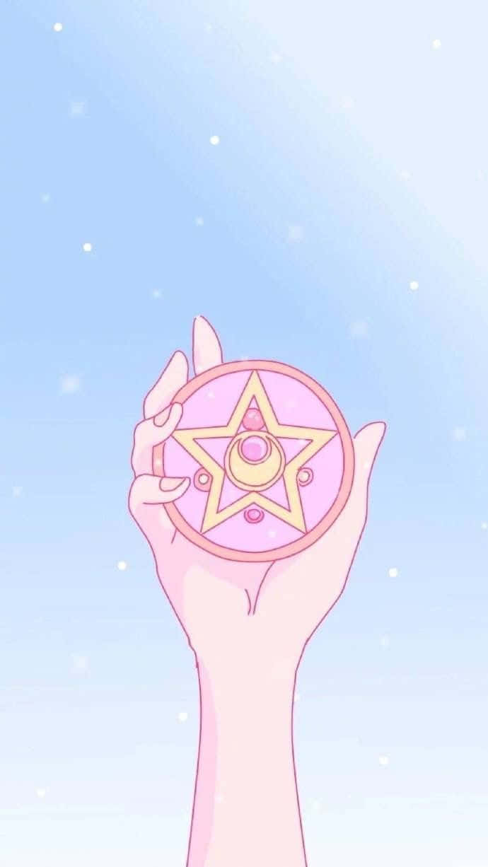 美少女戰士 桌布 壁紙 — 一隻手拿著粉紅色星形魔法棒，背景是柔和的藍天，帶有閃爍的粒子。