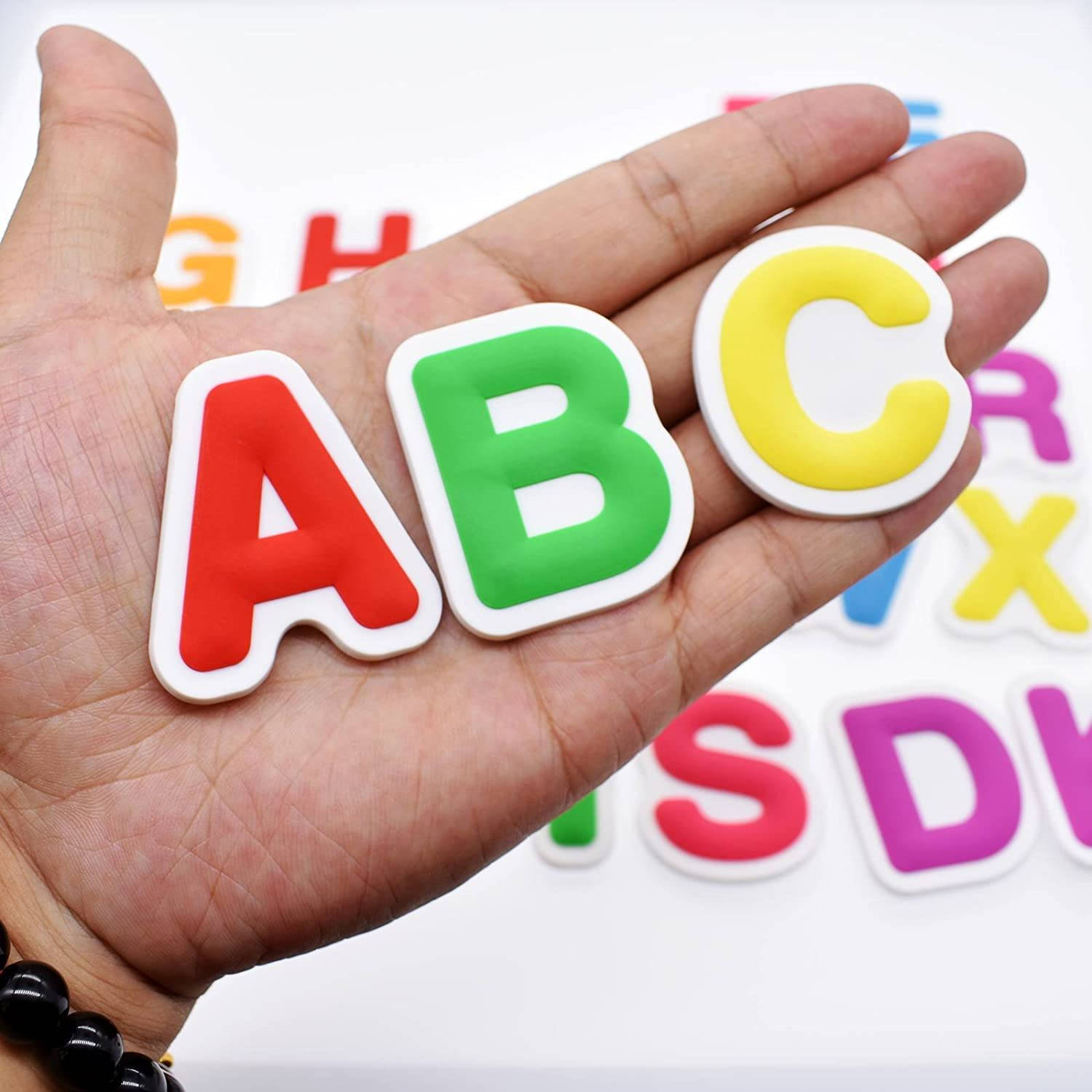 abc 桌布 壁紙 — 一隻手拿著色彩繽紛的3D字母ABC，背景是白色表面上更多的字母。