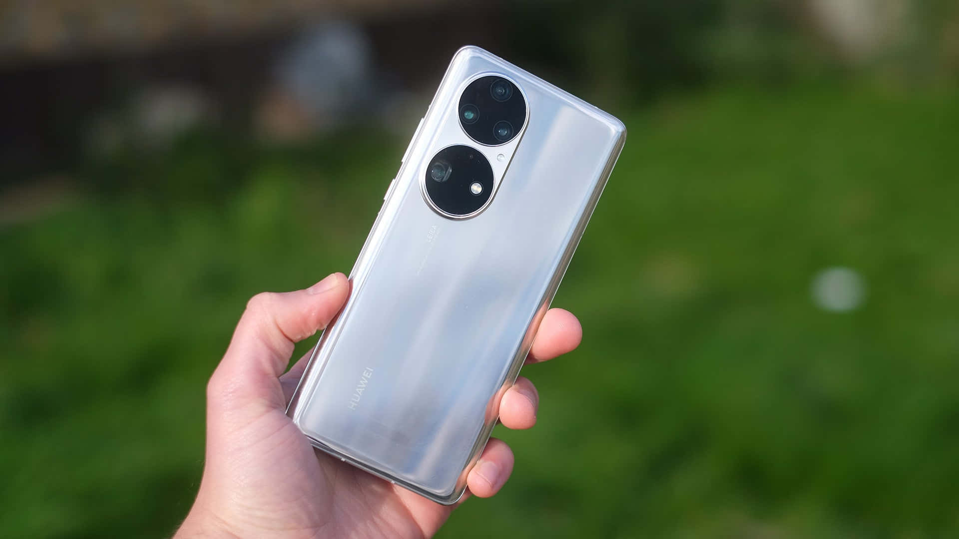 戶外手持銀色Huawei手機，帶有雙相機模組。