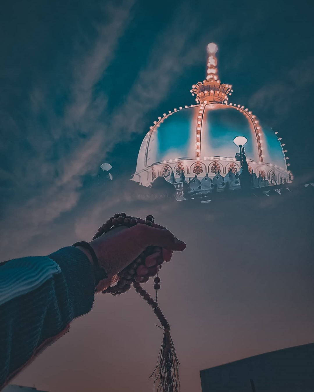 教堂 桌布 壁紙 — 一隻手持念珠伸向發光的圓頂寺廟，背景是暮色天空和縷縷雲彩。
