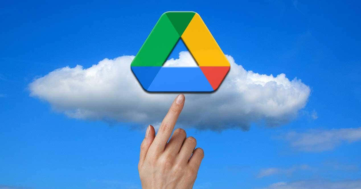 google 桌布 壁紙 — 一隻手指向上方，指向漂浮在蓬鬆白雲之上、藍天背景中的 Google Drive 標誌。