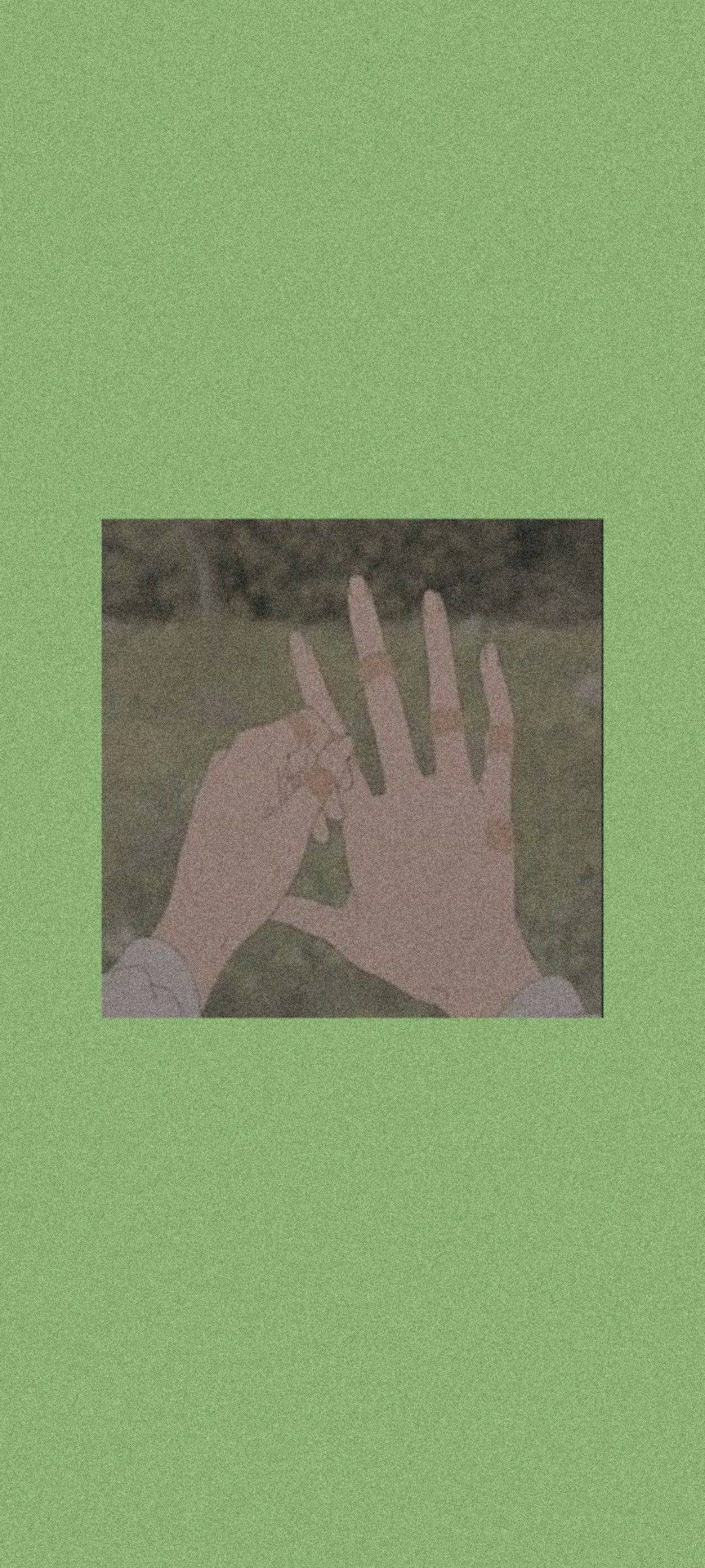 Green Anime Aesthetic 桌布 壁紙 — 一隻手指張開的手，襯托著柔和的綠色背景，由柔和自然光線和模糊的樹葉框著。