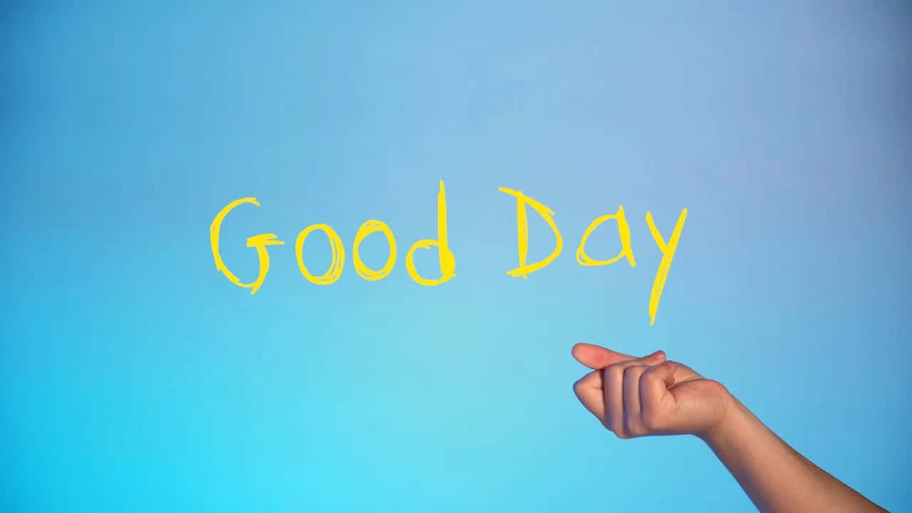  壁紙 — 一隻手指指向平滑藍色背景上以黃色粉筆寫成的「Good Day」字樣。
