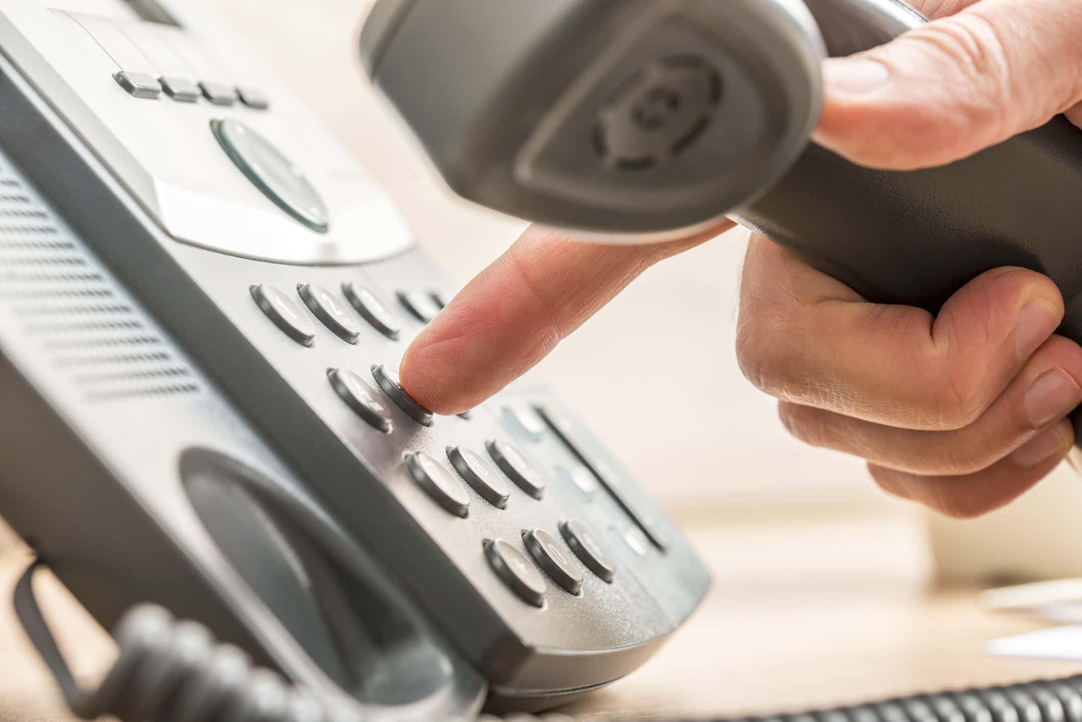 Telemarketing 桌布 壁紙 — 一隻手按下灰色辦公室電話按鈕的特寫，聽筒已拿起。
