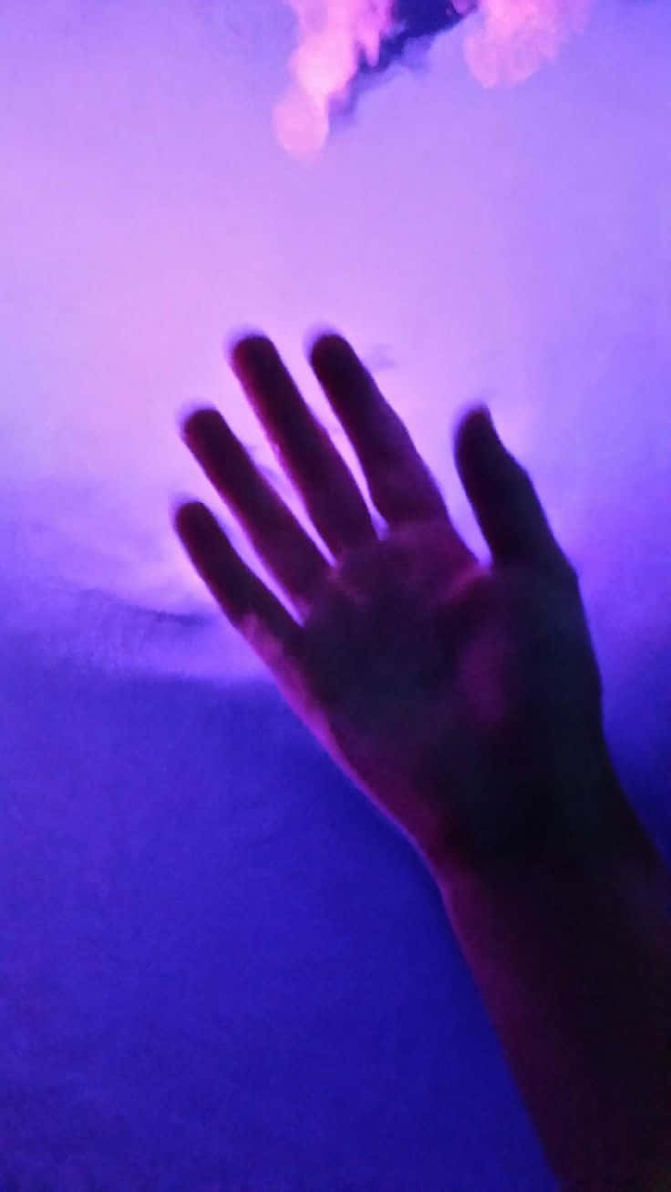 Violet Aesthetic 桌布 壁紙 — 一隻手按在玻璃窗上，沐浴在充滿活力的紫色和藍色光線中，上方有柔和發光的形狀。