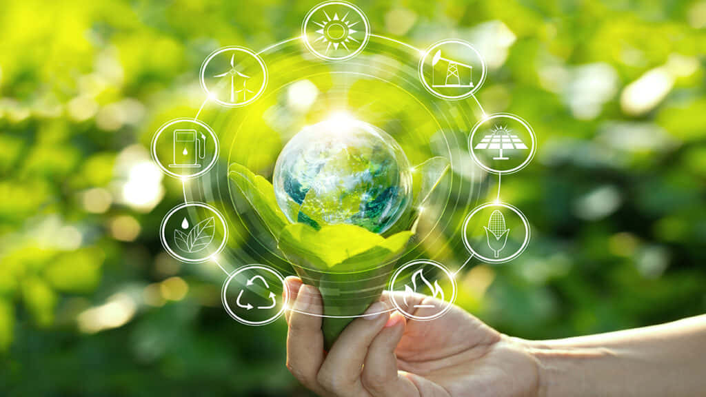 Green Technology 桌布 壁紙 — 一隻手捧著一個發光的地球，周圍環繞著環保圖標，背景是陽光普照的綠色樹葉。