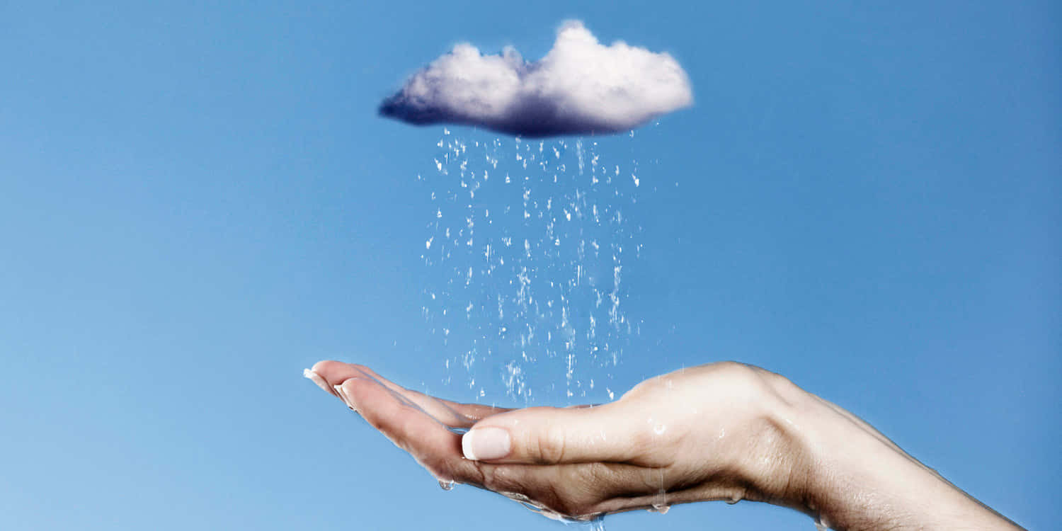 下雨 桌布 壁紙 — 一隻手捧著一朵小雲，雲朵正降下清澈的水滴，映襯著明亮的藍天。