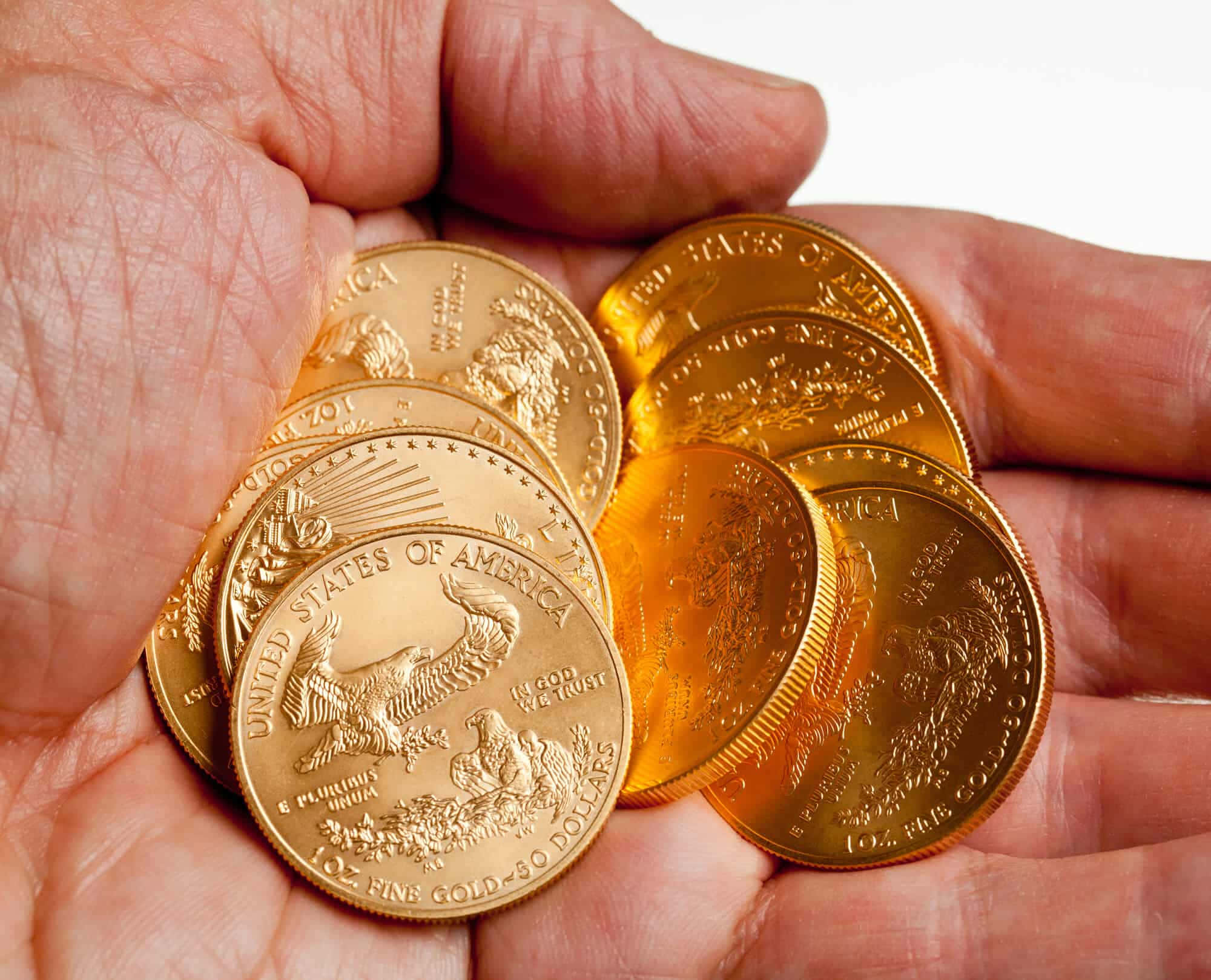 金色動態 桌布 壁紙 — 一隻手捧著幾枚閃閃發光的美國鷹揚金幣，背景是明亮的白色。