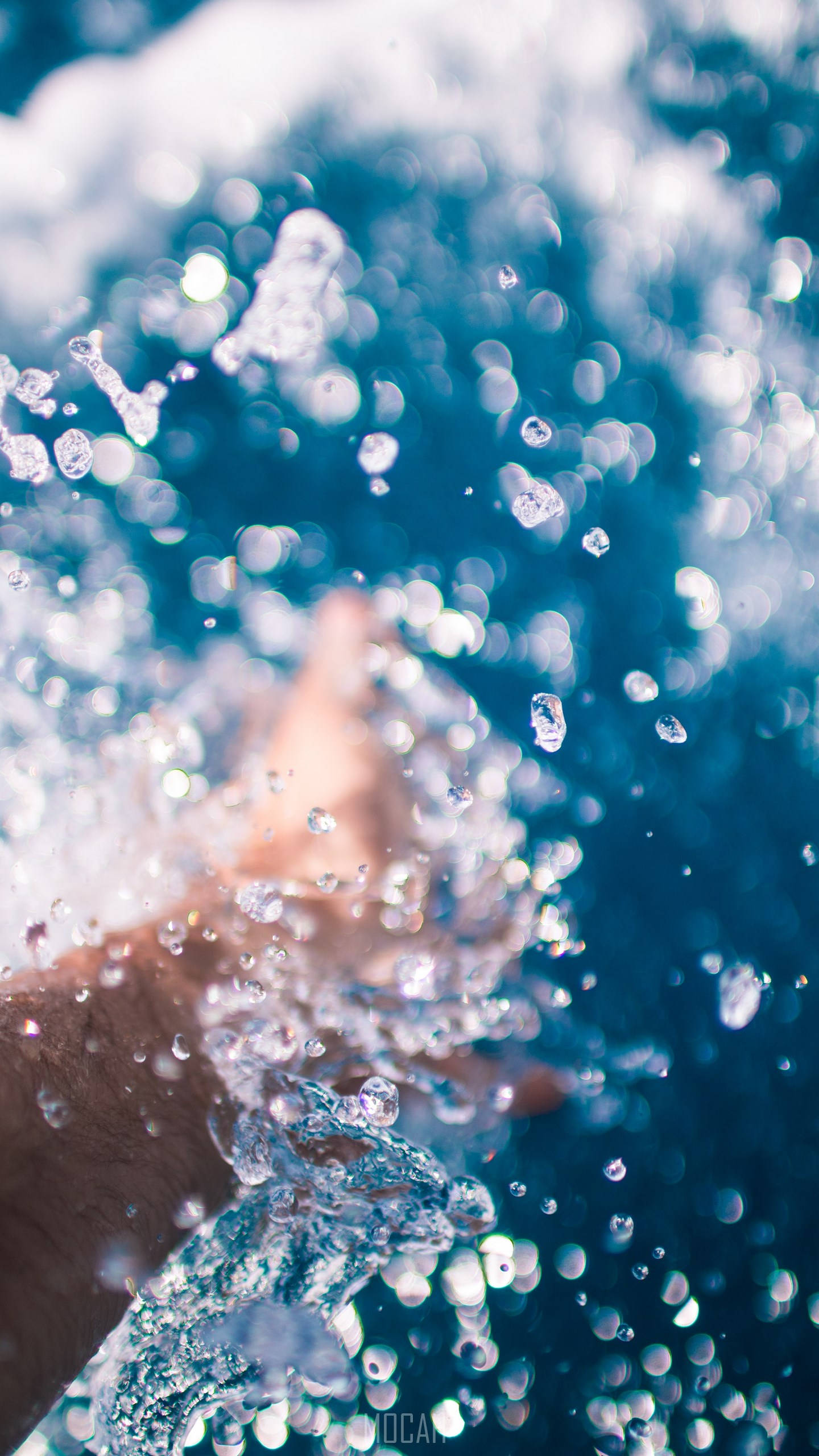 Water Splash 桌布 壁紙 — 一隻手插入充滿活力的藍色水中，產生閃爍的水滴和閃爍的光折射。