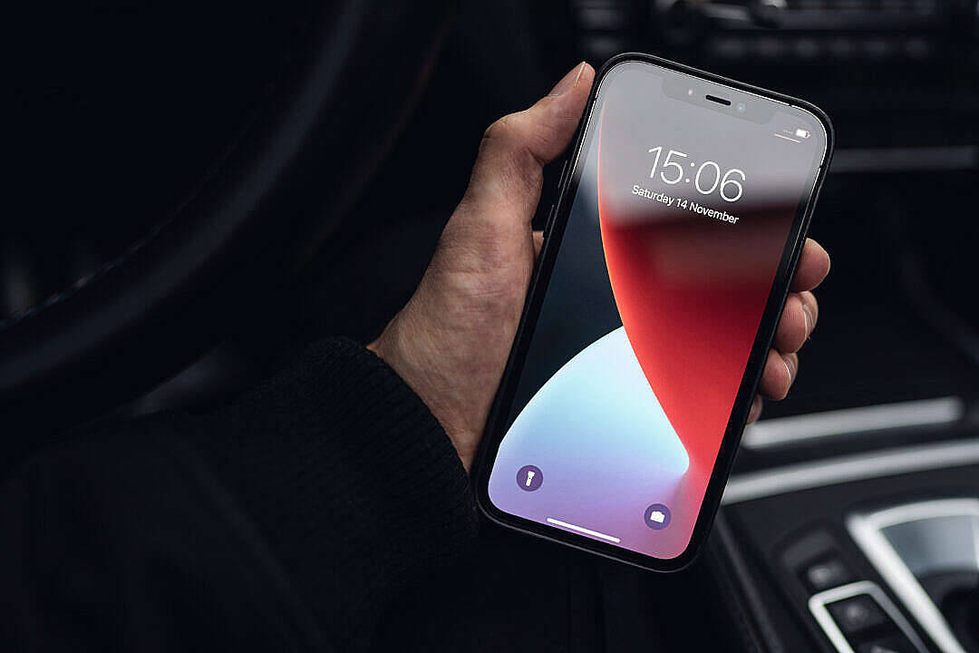 Valorant iPhone 壁紙 桌布 壁紙 — 一隻手握住一支智慧型手機，在車內顯示紅藍漸變桌布。